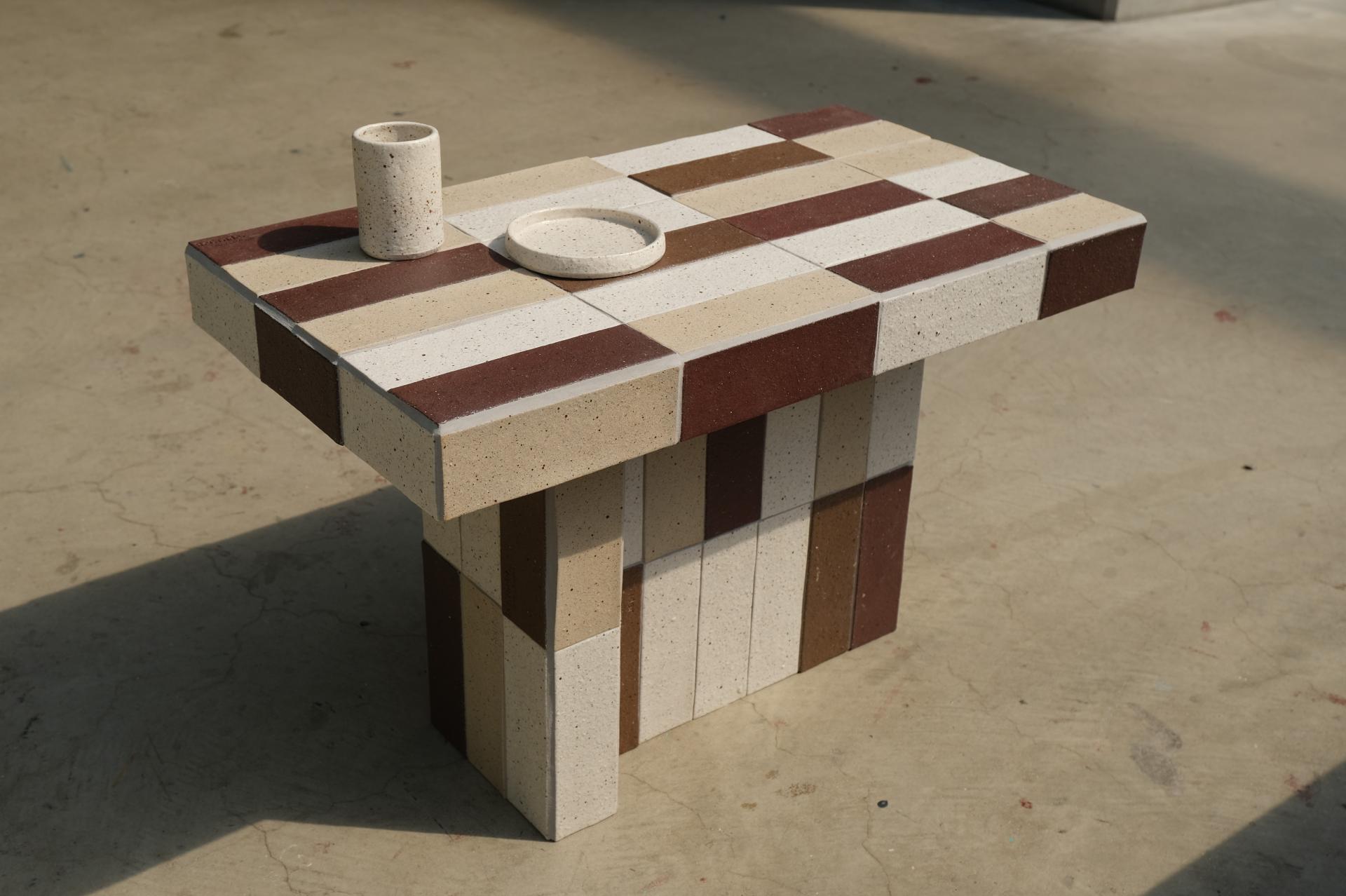 Stylish table made from waste-based materials, showcasing regenerative design with a unique color pattern and eco-friendly aesthetic.