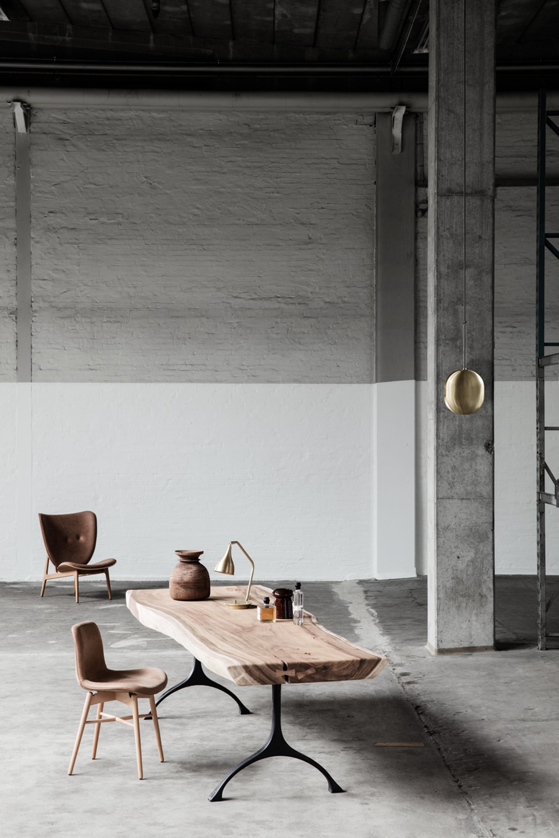 Stylish wooden dining table with modern chairs and decorative elements in an industrial space at designjunction.