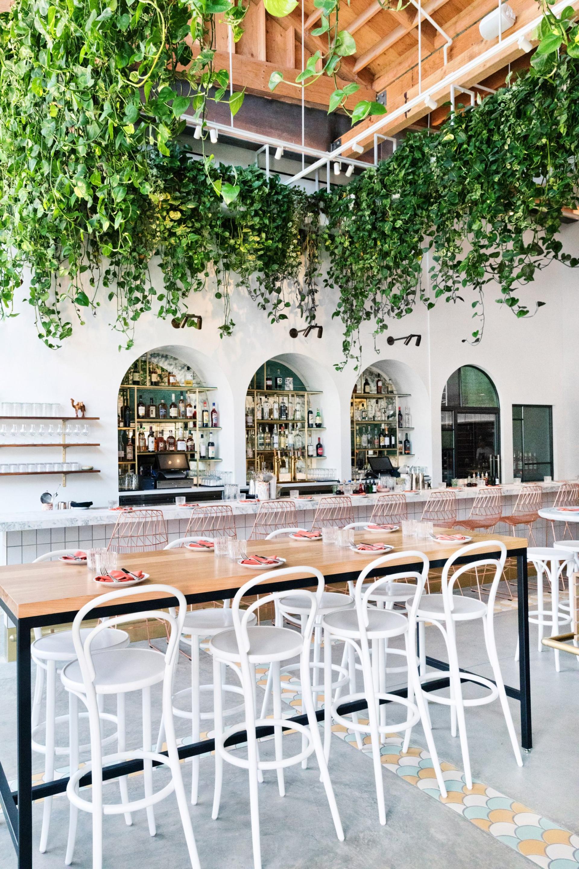 Modern restaurant interior by Studio Unltd featuring lush greenery, stylish seating, and a vibrant bar area inspired by Moroccan design.