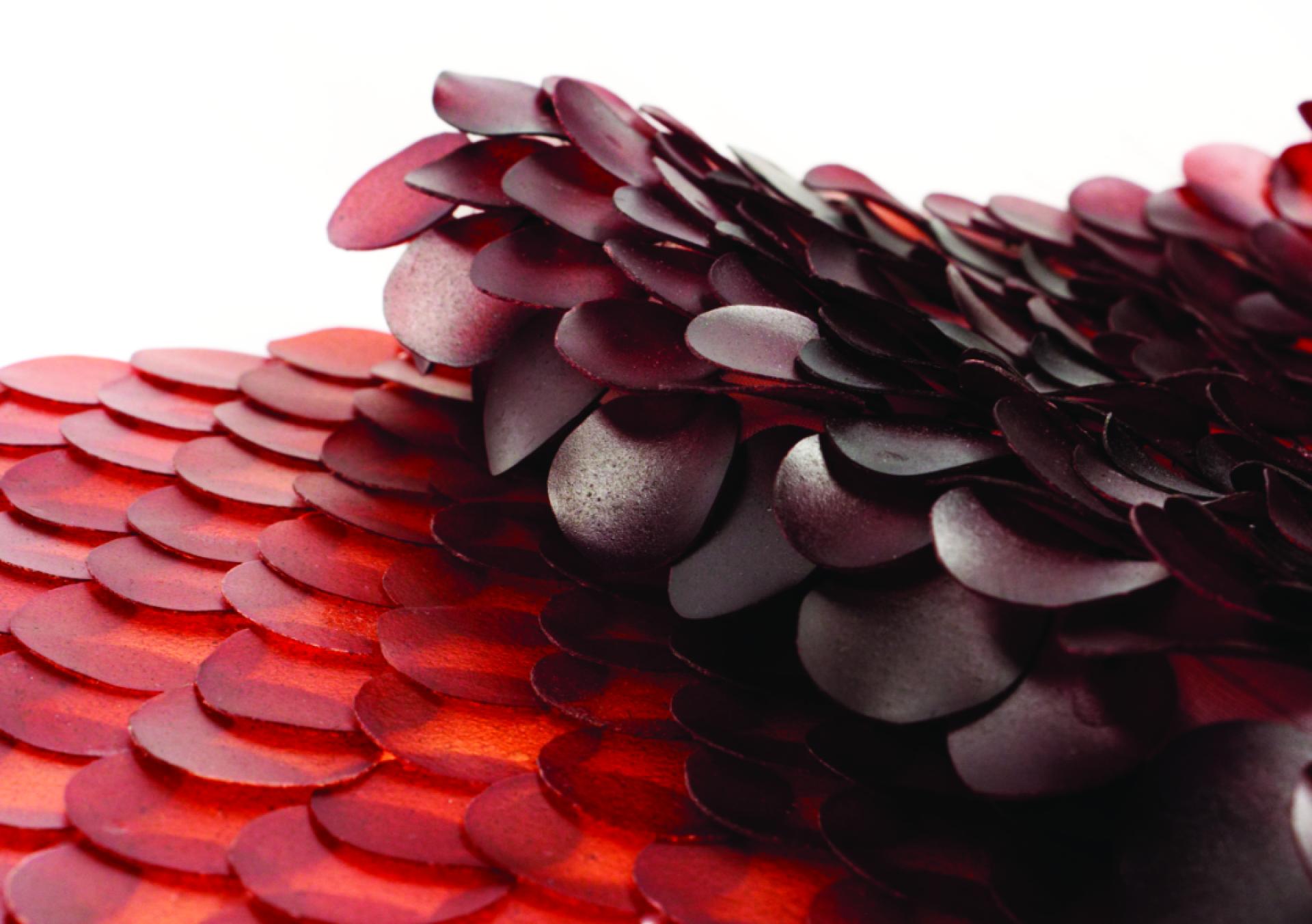 Textured biomaterials in shades of red and black, showcasing innovative design for sustainable applications in fashion and art.