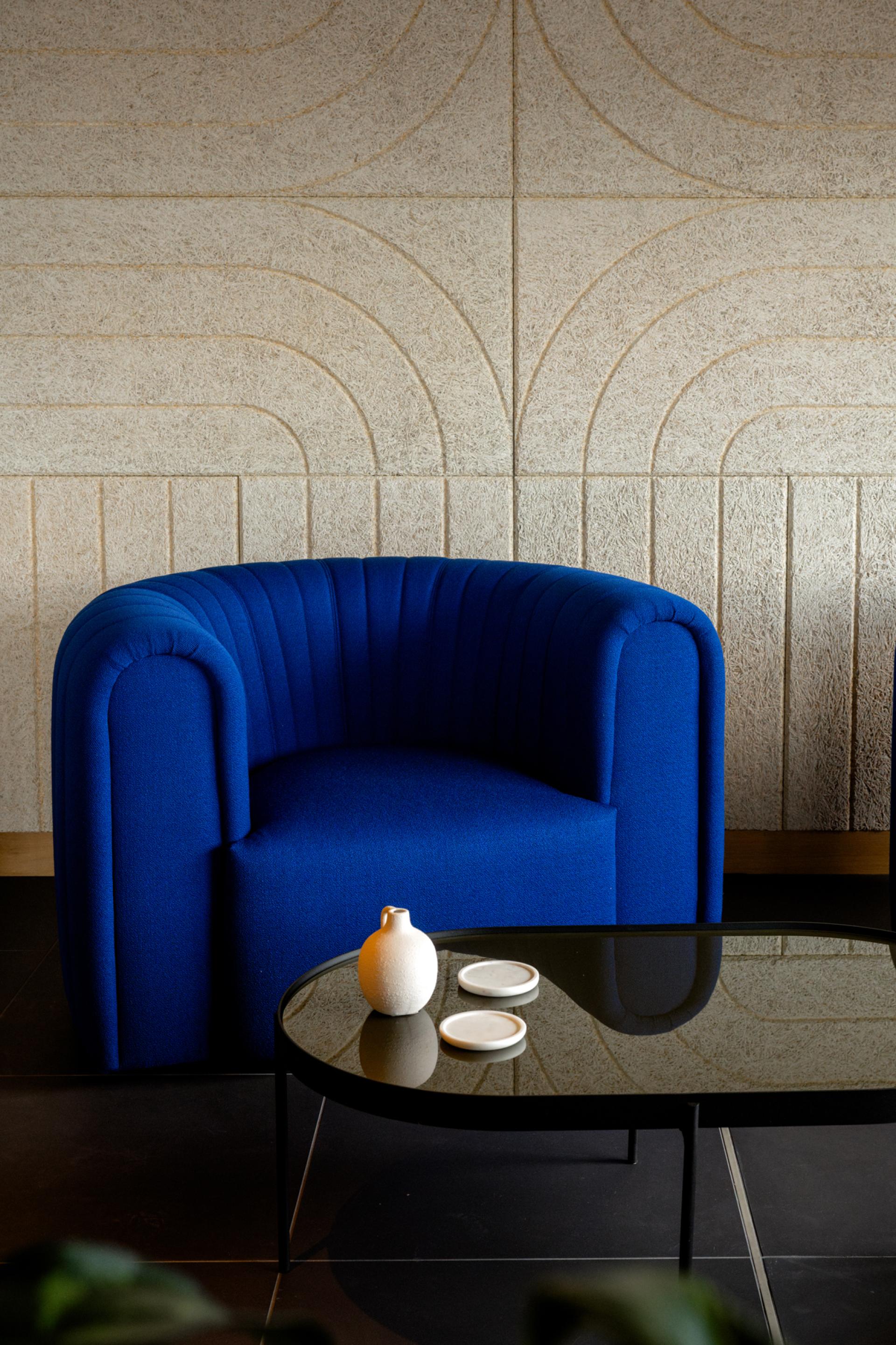 Bright blue armchair paired with a sleek black table, showcasing Scotland's design essence in Dentons' Edinburgh workspace.