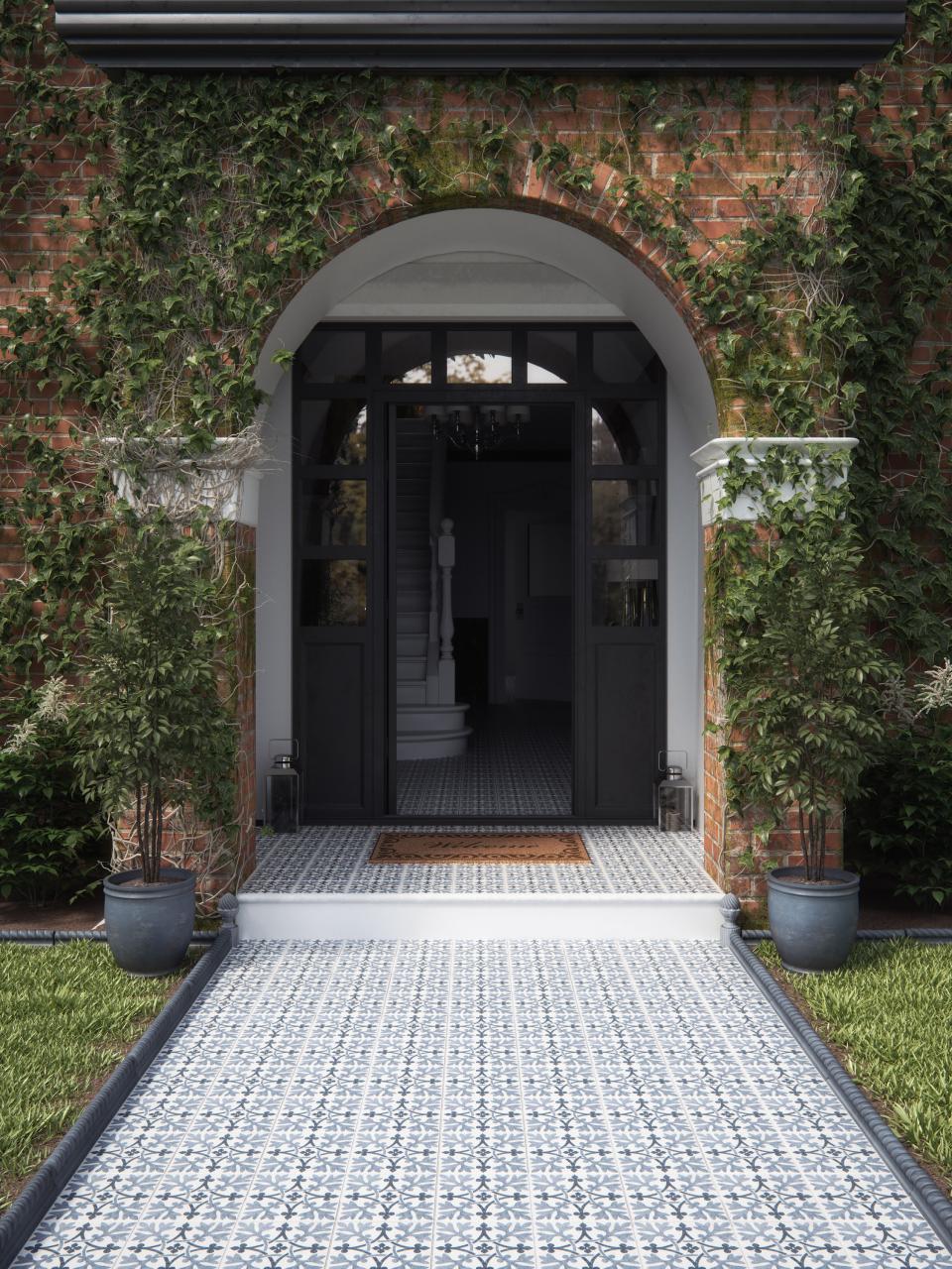 Sophisticated ceramic tiles adorn the entrance pathway, enhancing the elegance of this beautifully landscaped home.