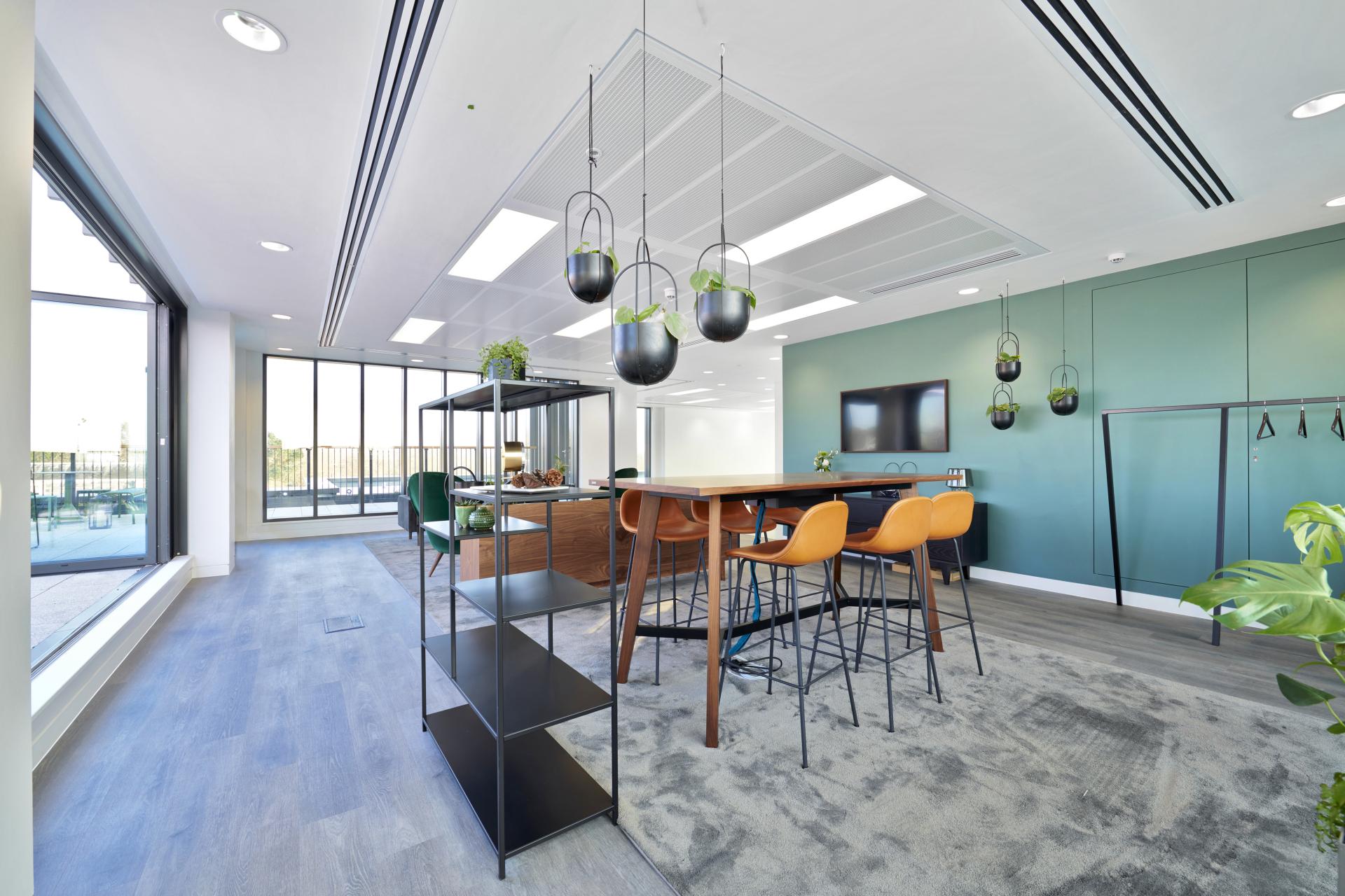 Modern office interior by SpaceInvader featuring nature-inspired decor, a stylish bar table, and hanging plants.