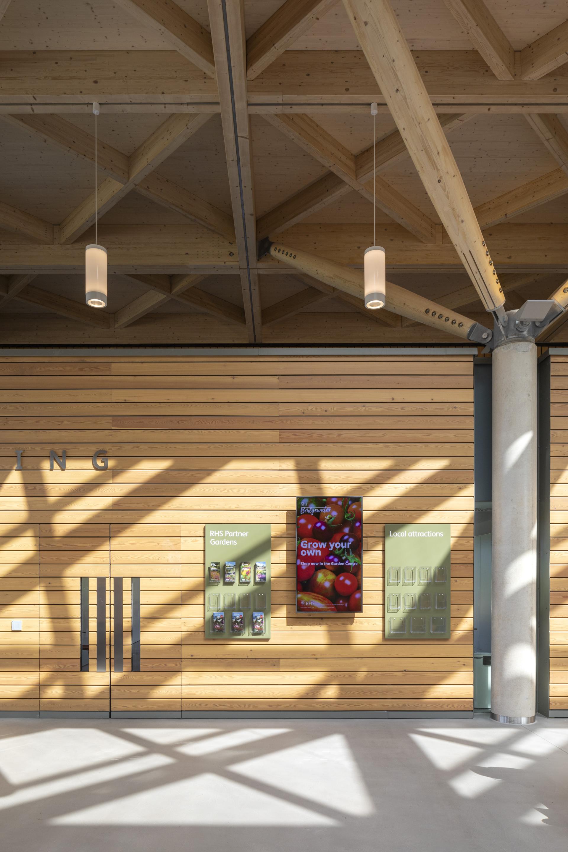 Modern interior of RHS Bridgewater featuring wooden walls, informational displays, and elegant lighting design.