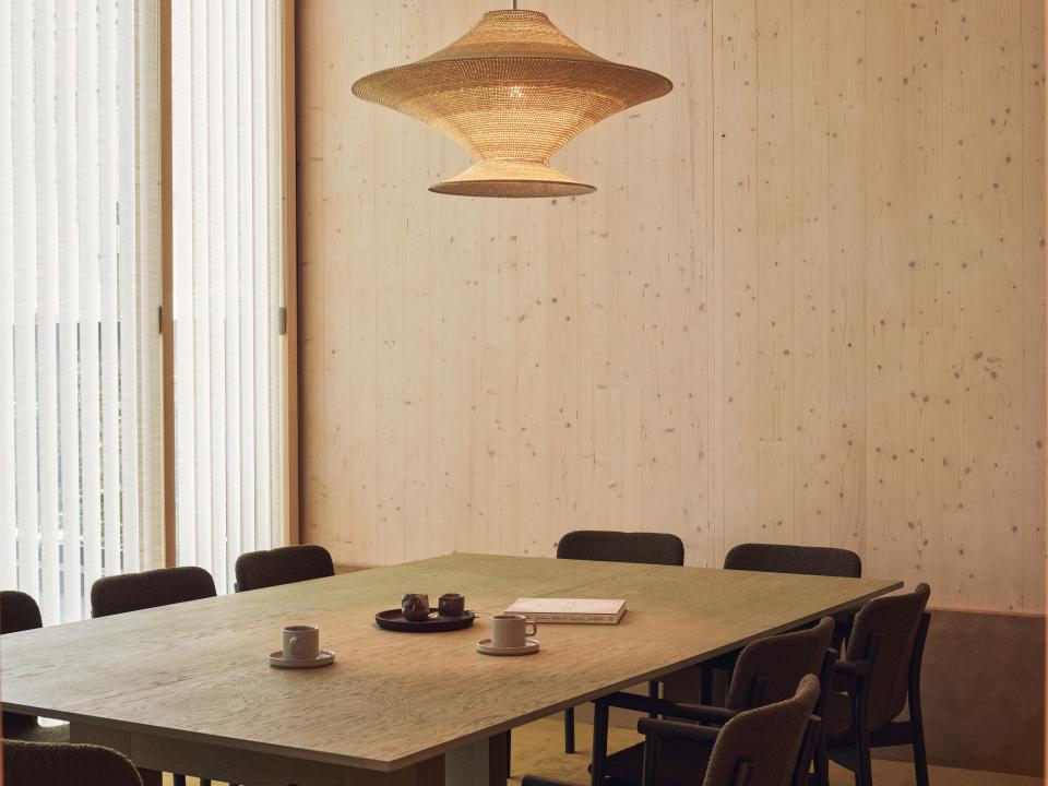 Contemporary interior of the Black & White Building featuring a wooden table, chairs, and natural light from window blinds.