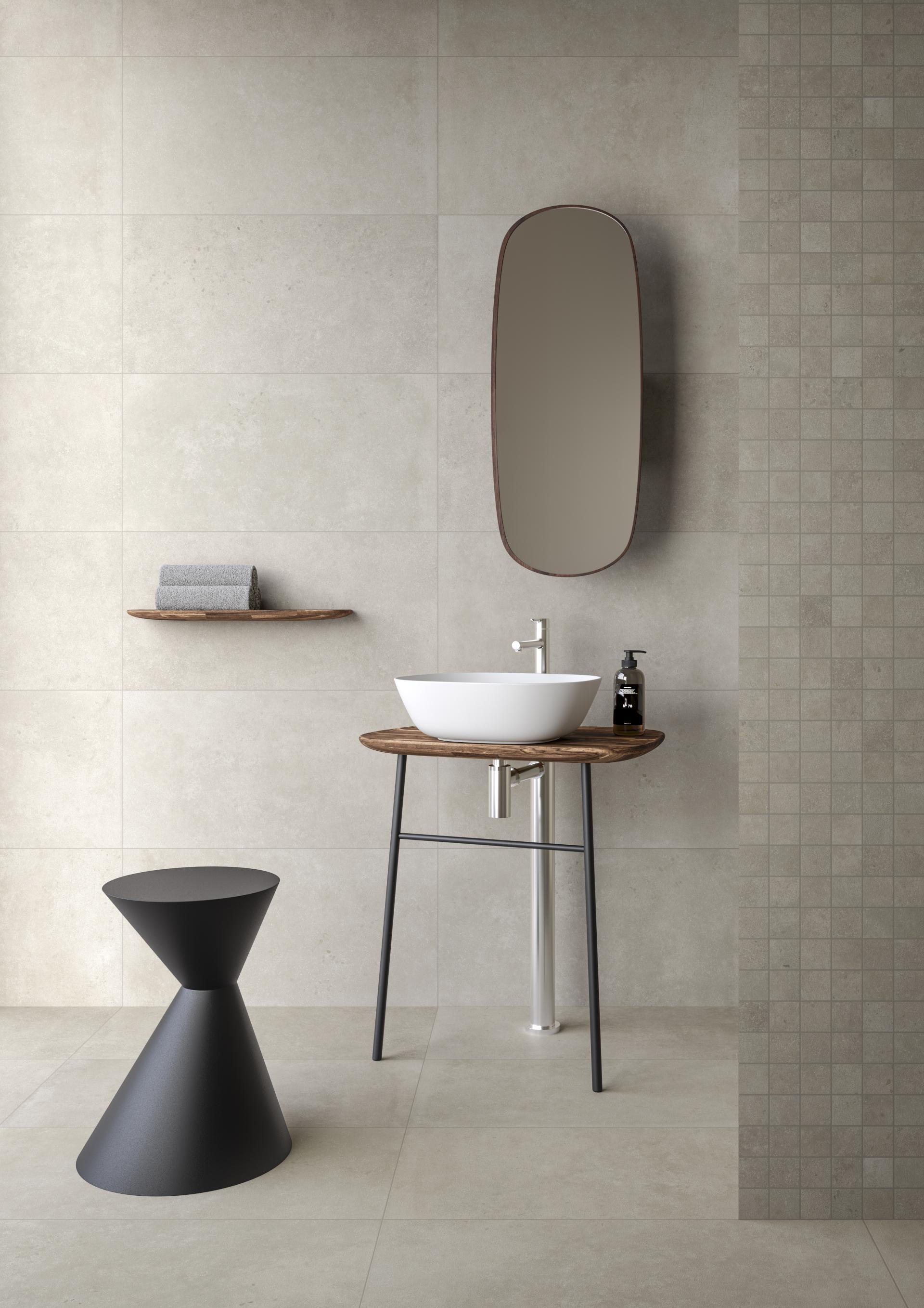 Stylish bathroom with textured tile walls, modern basin, wooden shelf, and contemporary black stool, showcasing VitrA's new designs.