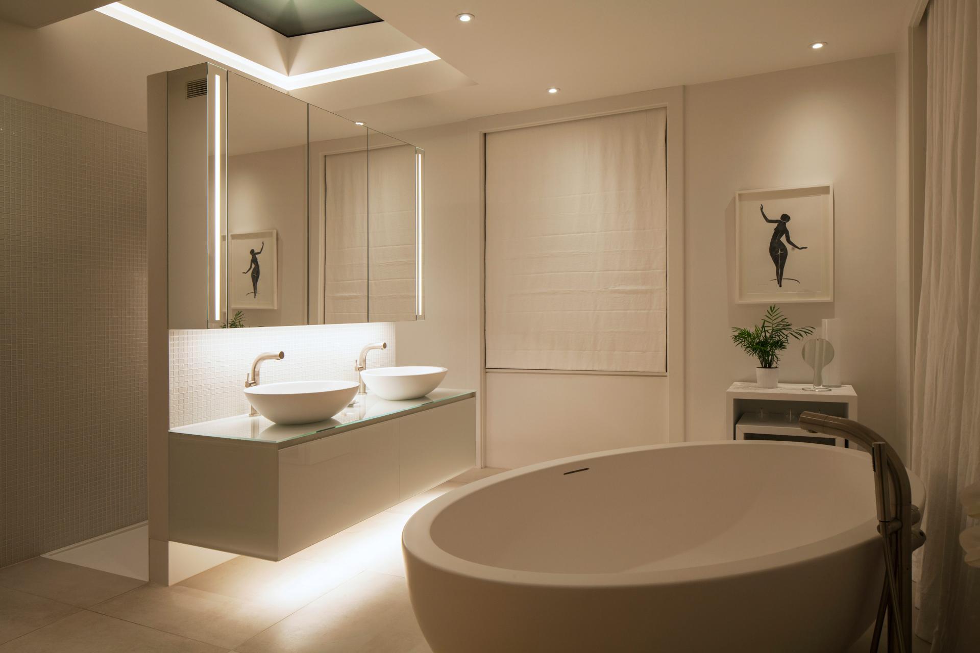 Modern bathroom design featuring elegant lighting, double sinks, and a freestanding tub, emphasizing Nulty's expertise in interior lighting.