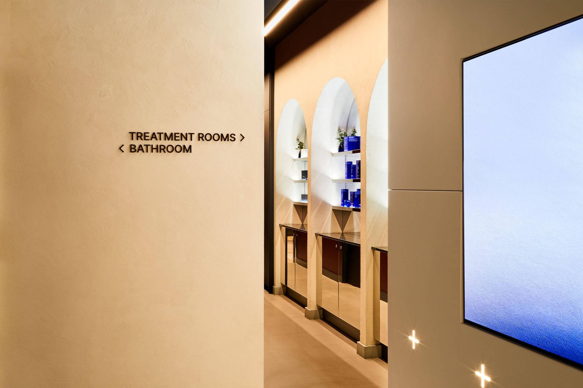 Elegant interior of Medika Clinic featuring directional signage for treatment rooms and bathroom, emphasizing a serene healthcare environment.