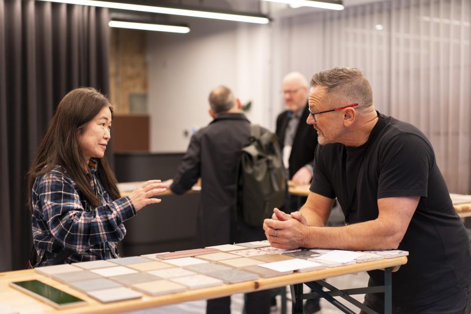 Attendees engage in discussion over material samples at the vibrant Material Source Studio celebration in Manchester.