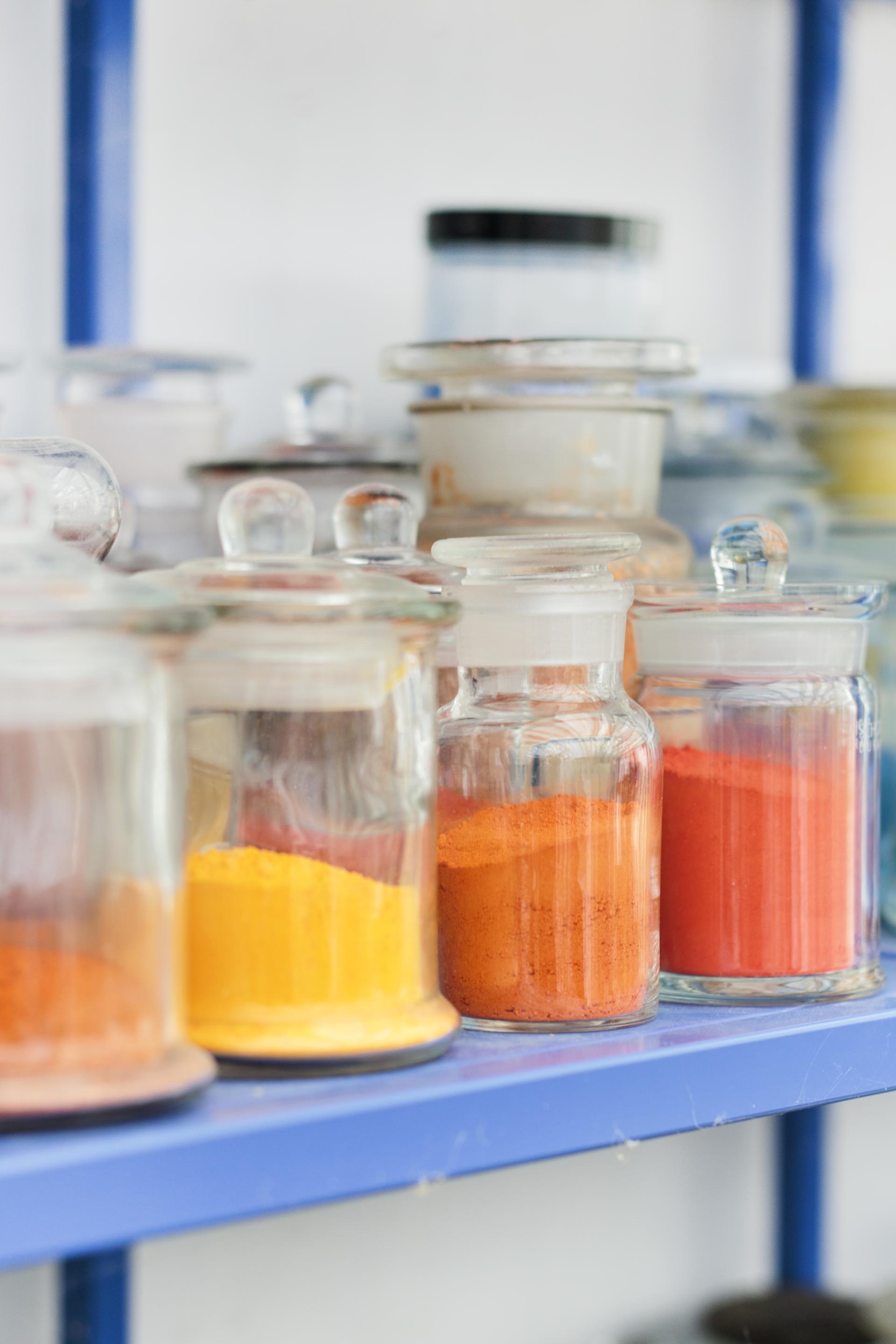 Colorful jars of pigments in various shades, showcasing Kvadrat’s vibrant approach to textile design at Salone del Mobile.