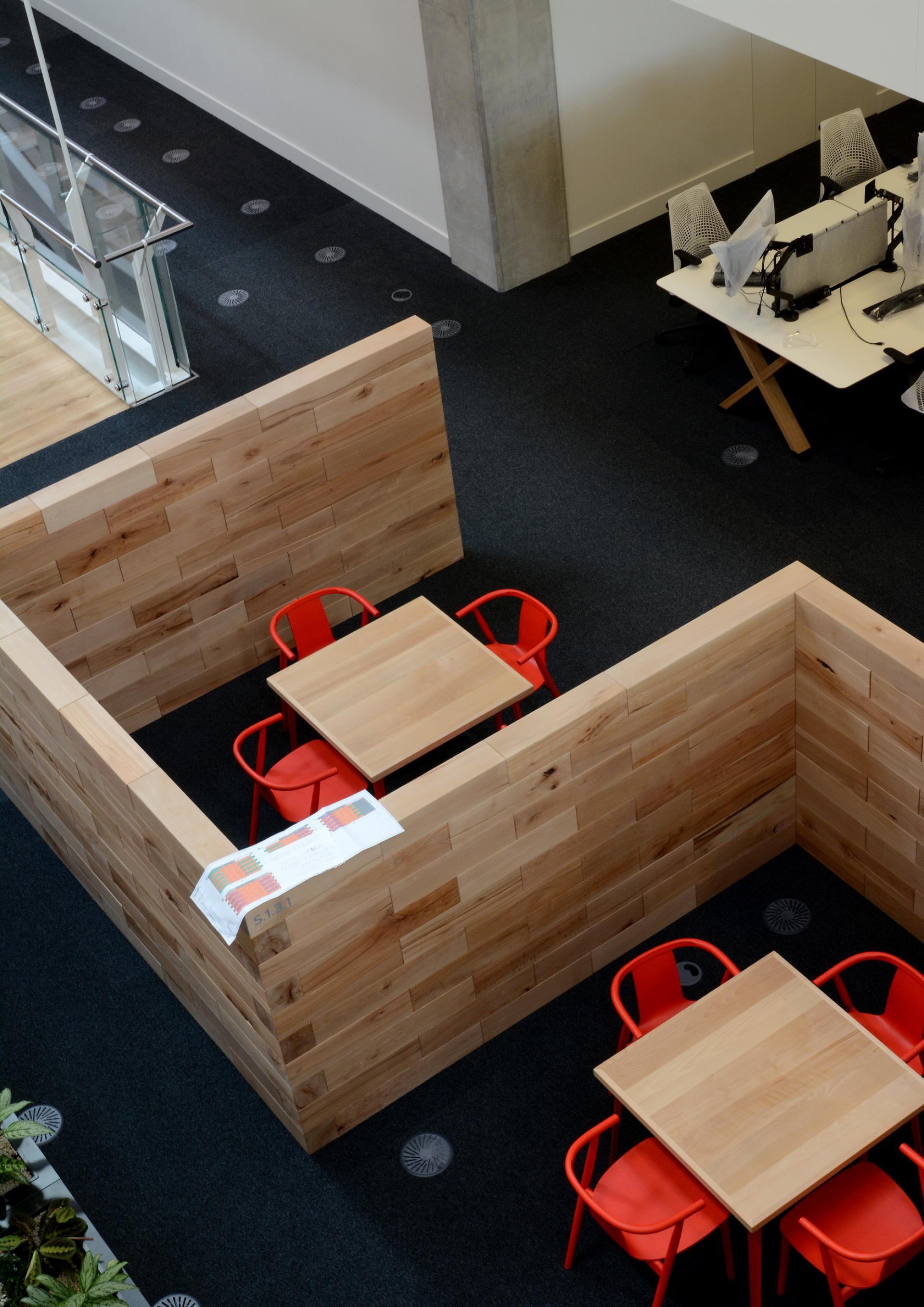 Modern wooden meeting space featuring natural materials, red chairs, and sustainable design aesthetics.