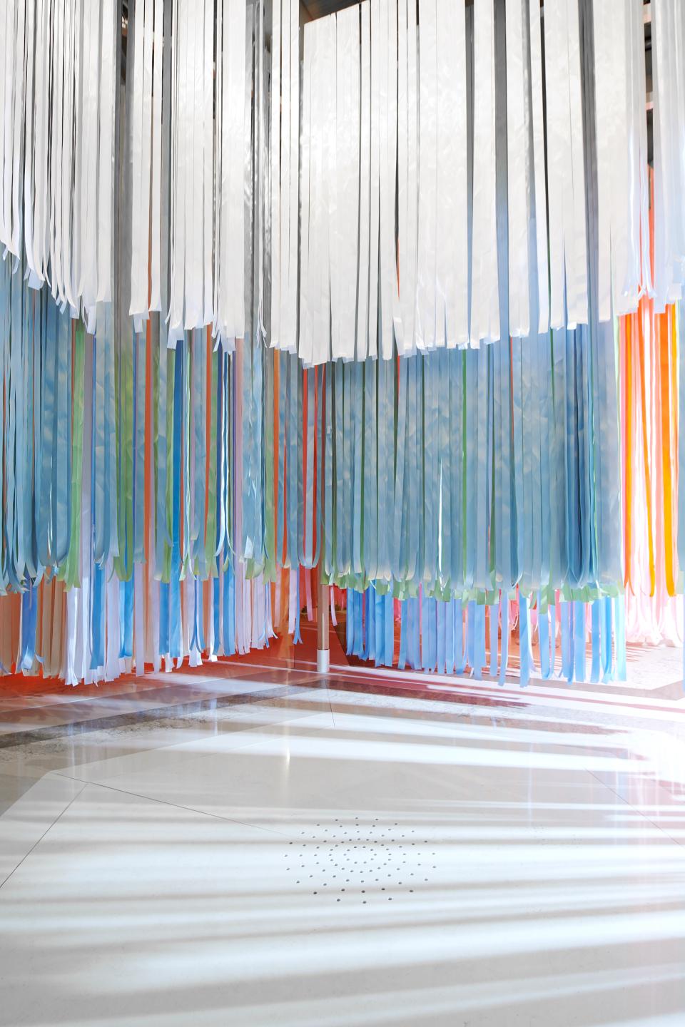 Colorful, flowing fabric ribbons hang from above, creating an immersive environment that highlights food design concepts by Caesarstone and Marije Vogelzang.