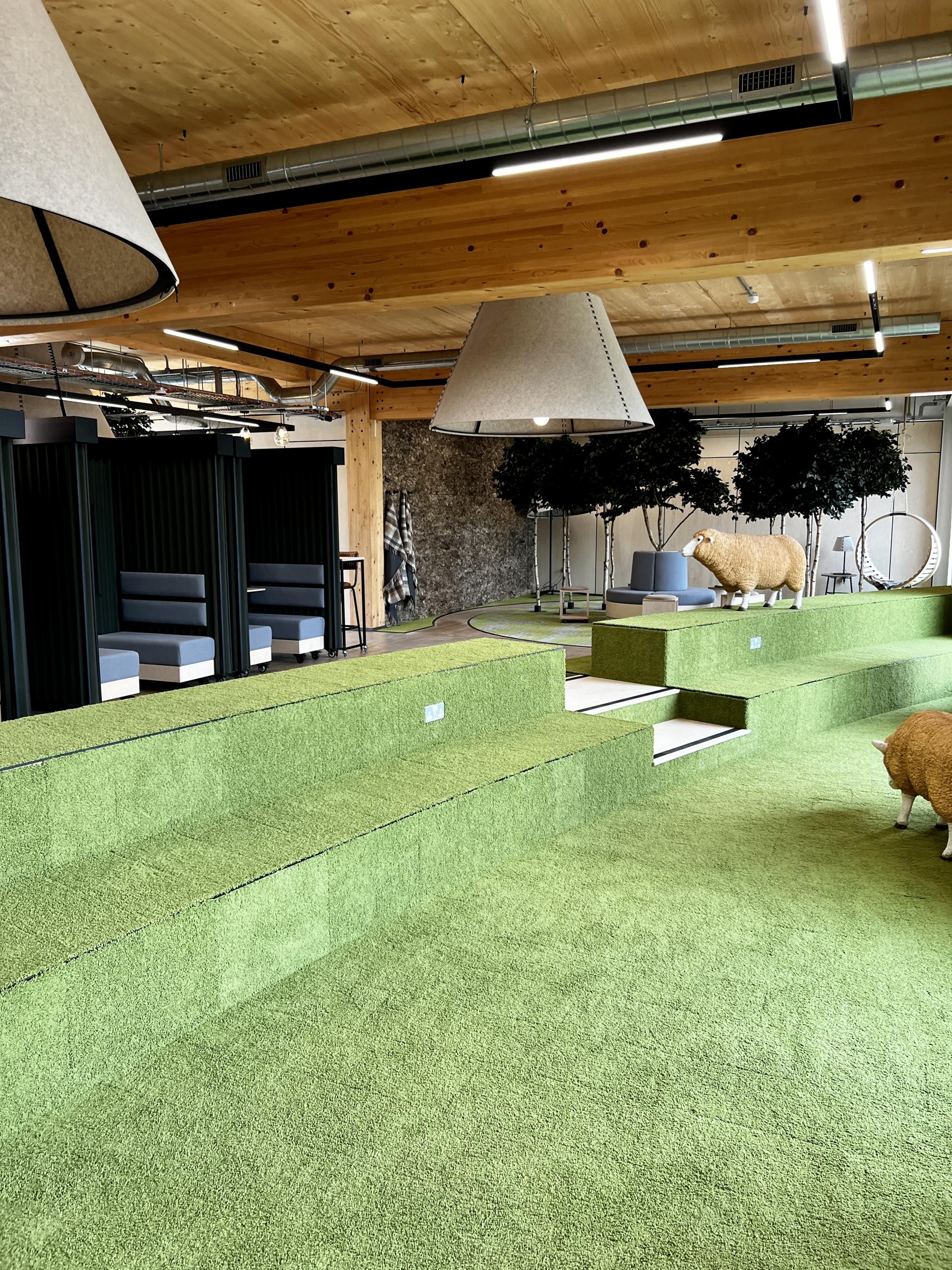 Innovative net zero carbon workspace interior featuring green turf, seating areas, and modern design elements promoting sustainability.