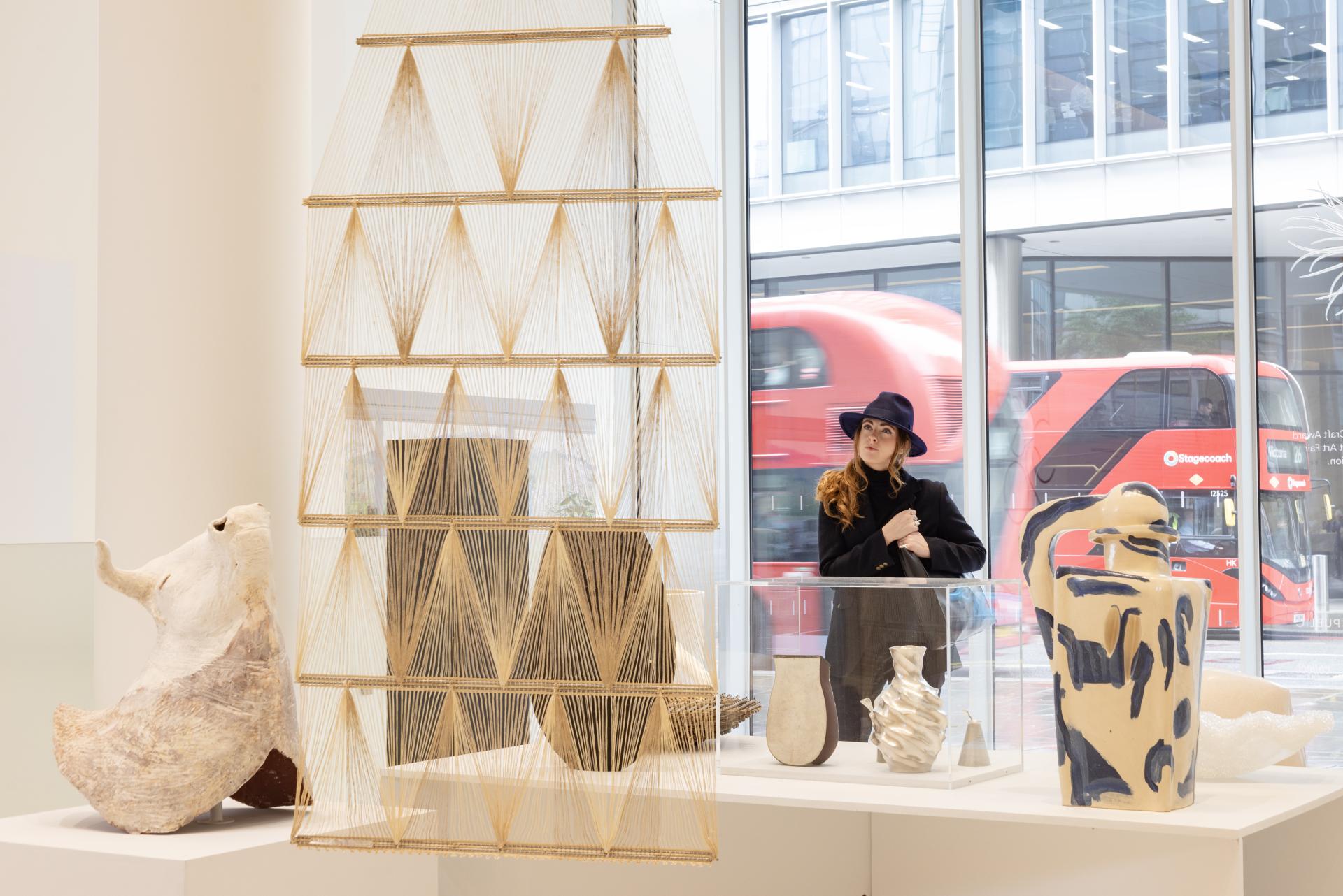 Sculptural ceramic artworks by Halima Cassell displayed in an art gallery, with a woman observing the pieces.