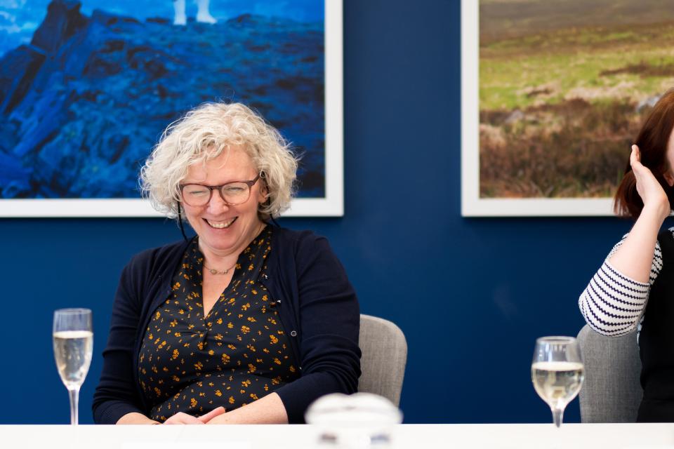 Smiling woman at a modern workplace meeting, representing collaboration and the human aspect of technology integration.