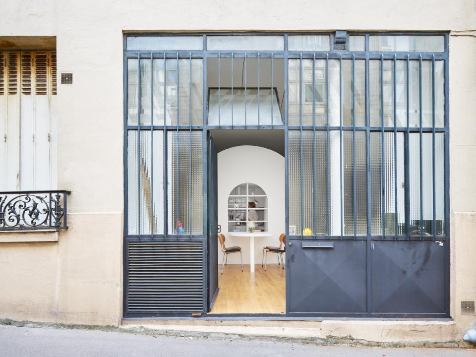 Modern Parisian home entrance with large glass doors, showcasing a bright, flexible living space inside.