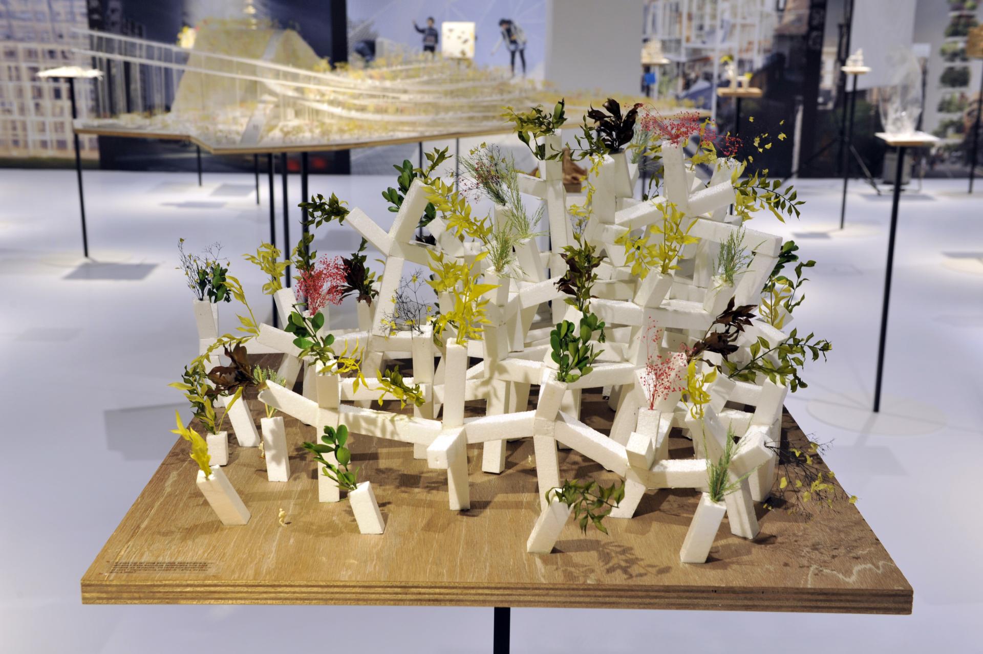 Architectural model featuring white structural elements intertwined with vibrant greenery at Sou Fujimoto's exhibit in Japan House London.