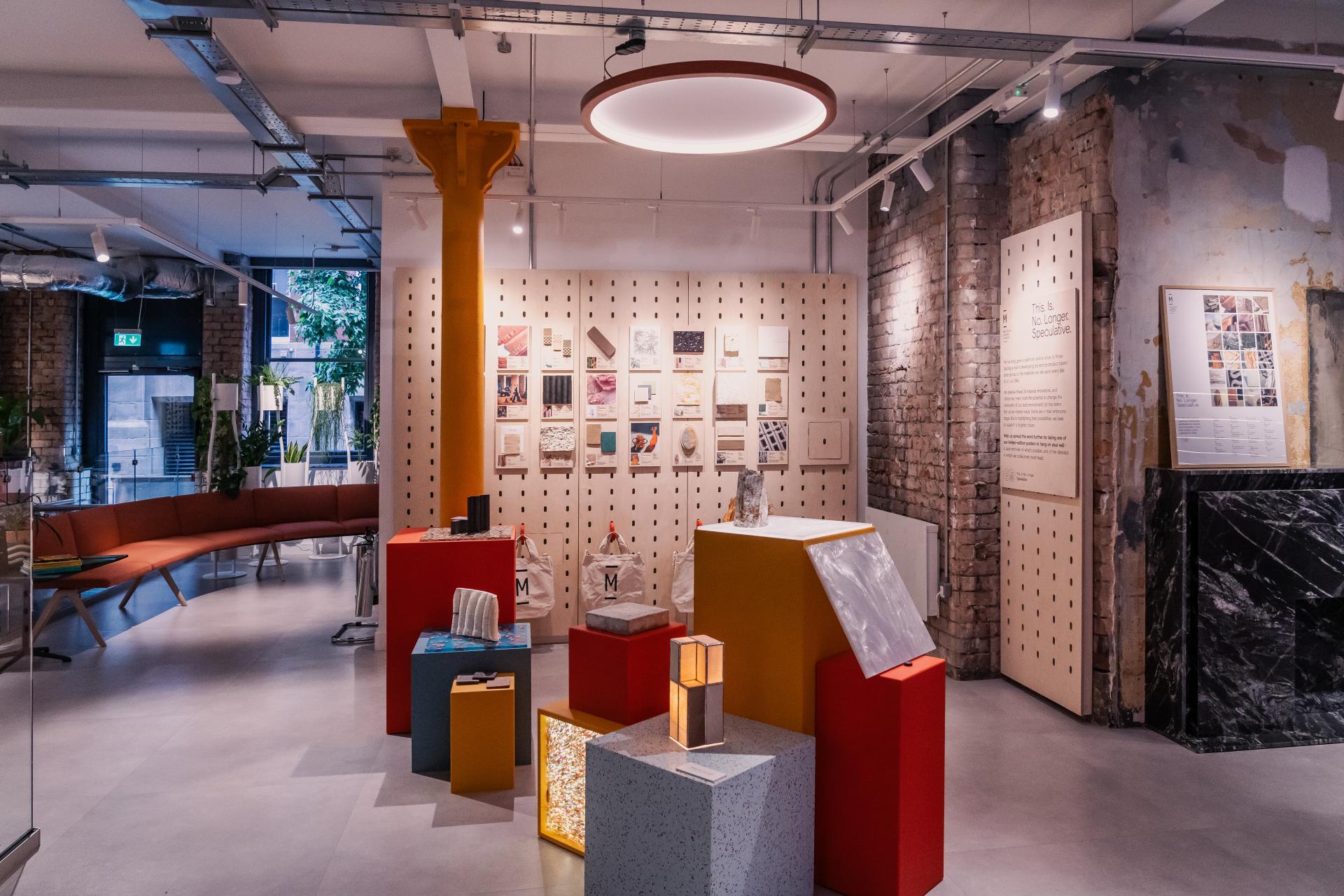 An art exhibition space showcasing by-product based materials and circular design concepts, with colorful displays and informational panels.