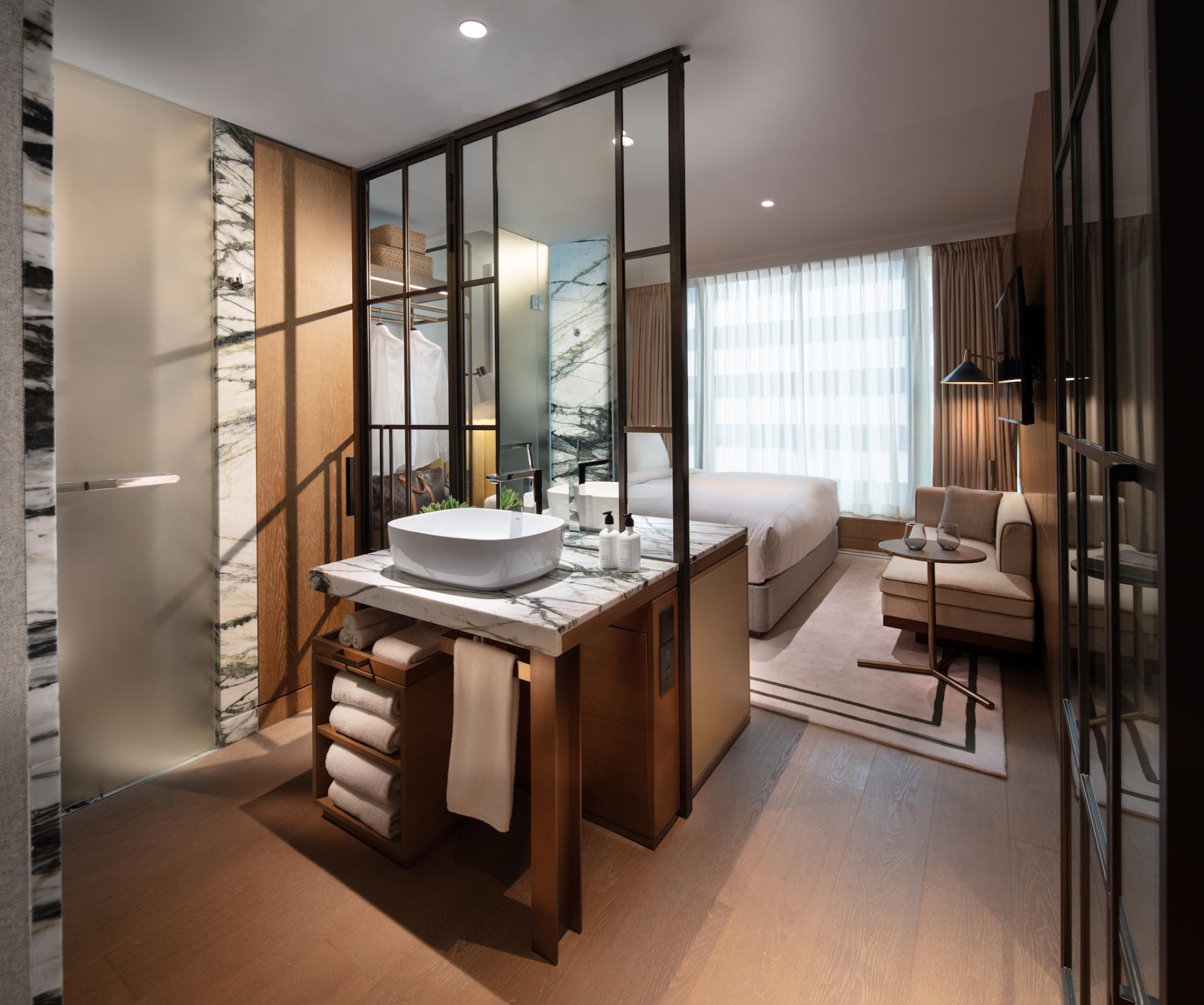 Stylish hotel room with a modern design featuring an elegant bathroom and spacious living area at The Hari Hong Kong.