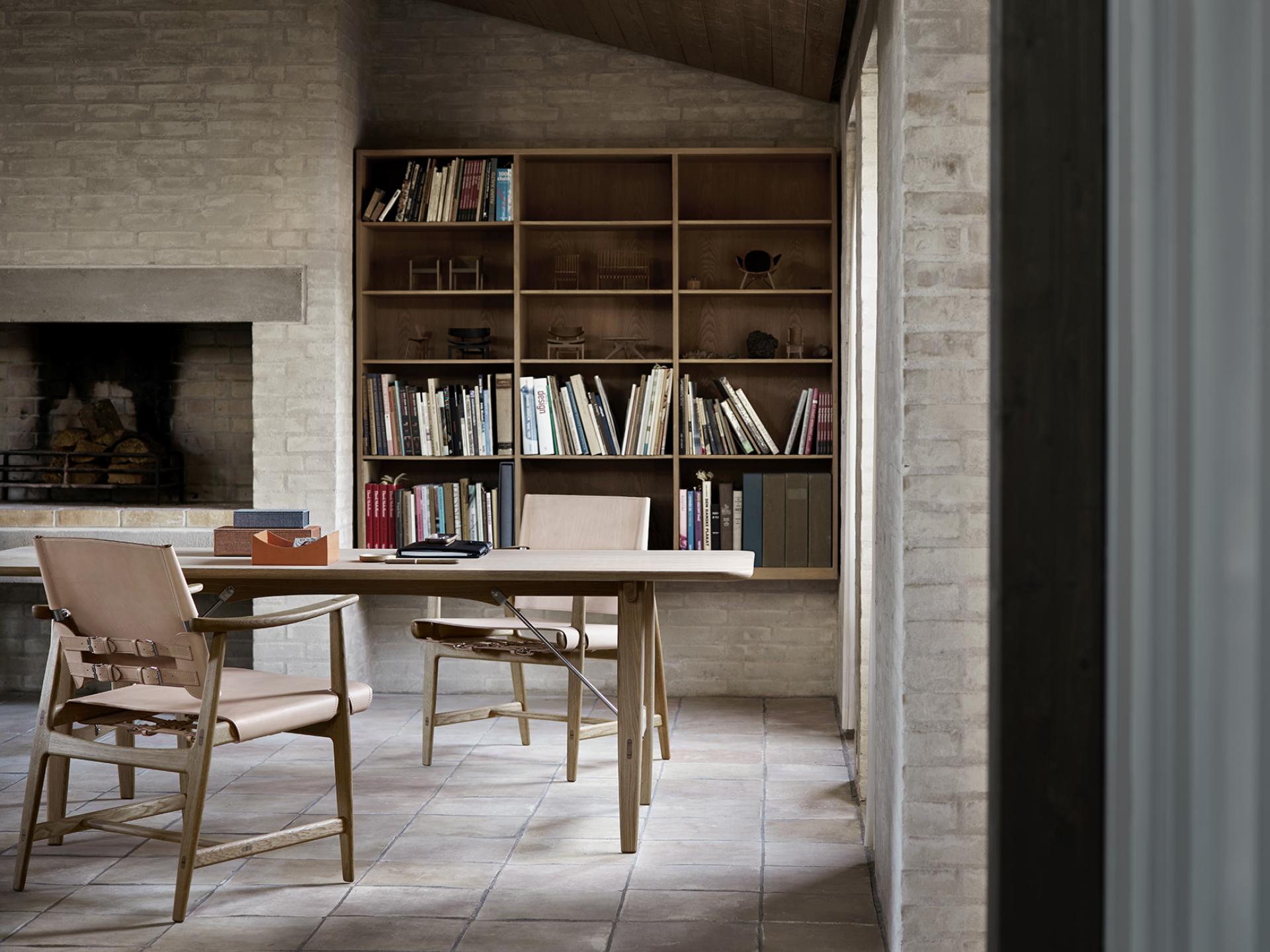 Elegant interior showcasing Børge Mogensen's Huntsman Chair alongside a modern wooden table and bookshelf, highlighting Danish design.