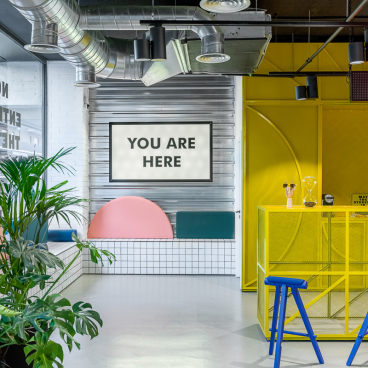 Vibrant co-working space at The Student Hotel Barcelona featuring a modern design with bold colors and greenery.