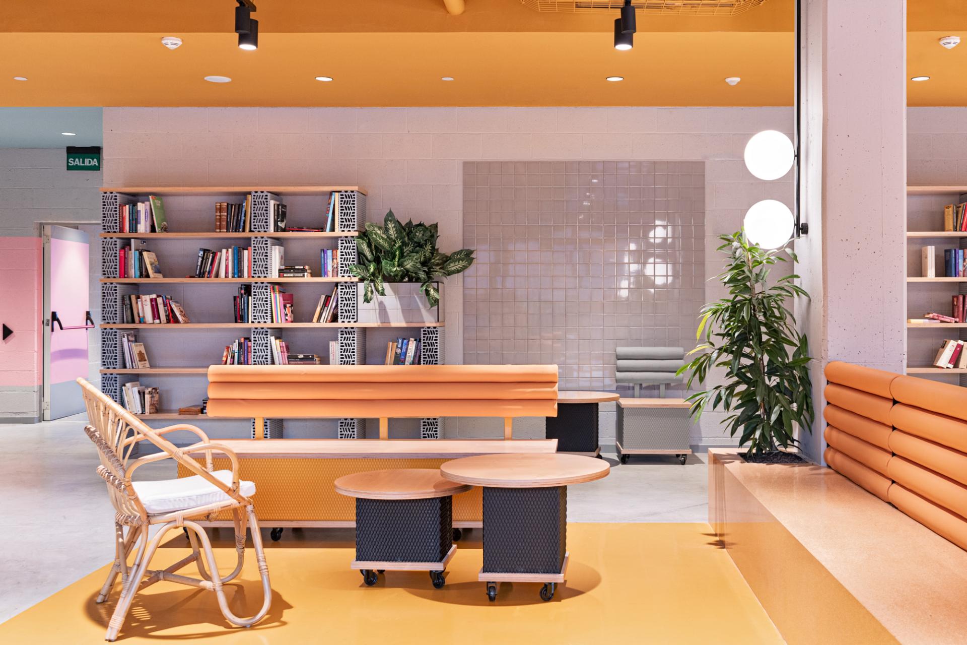 Colorful Wes Anderson-style interior of a student residence lounge, featuring bookshelves, modern seating, and vibrant decor.