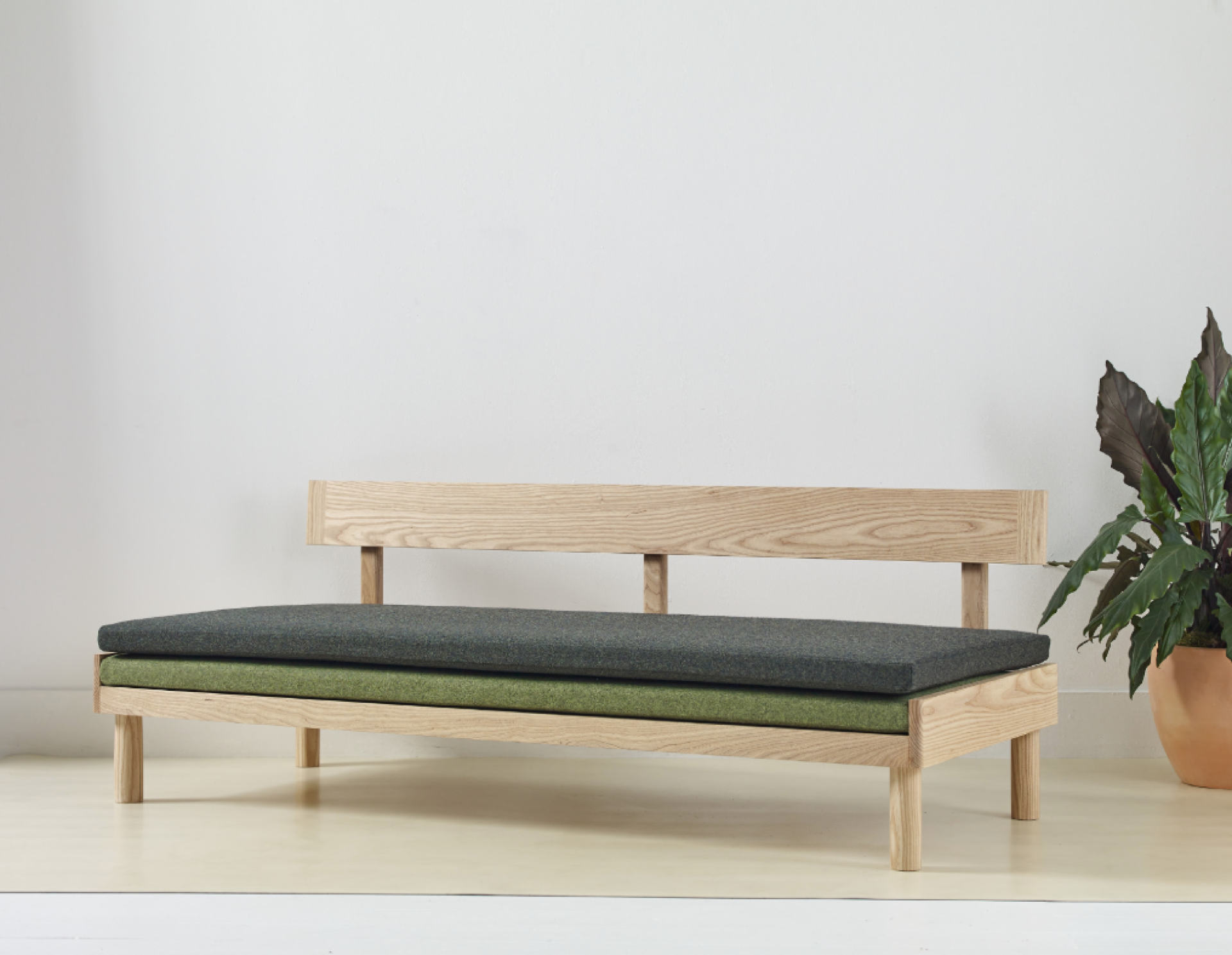 Sleek wooden bench with green and gray cushions, designed for wellbeing, enhancing home decor for the London Design Festival.