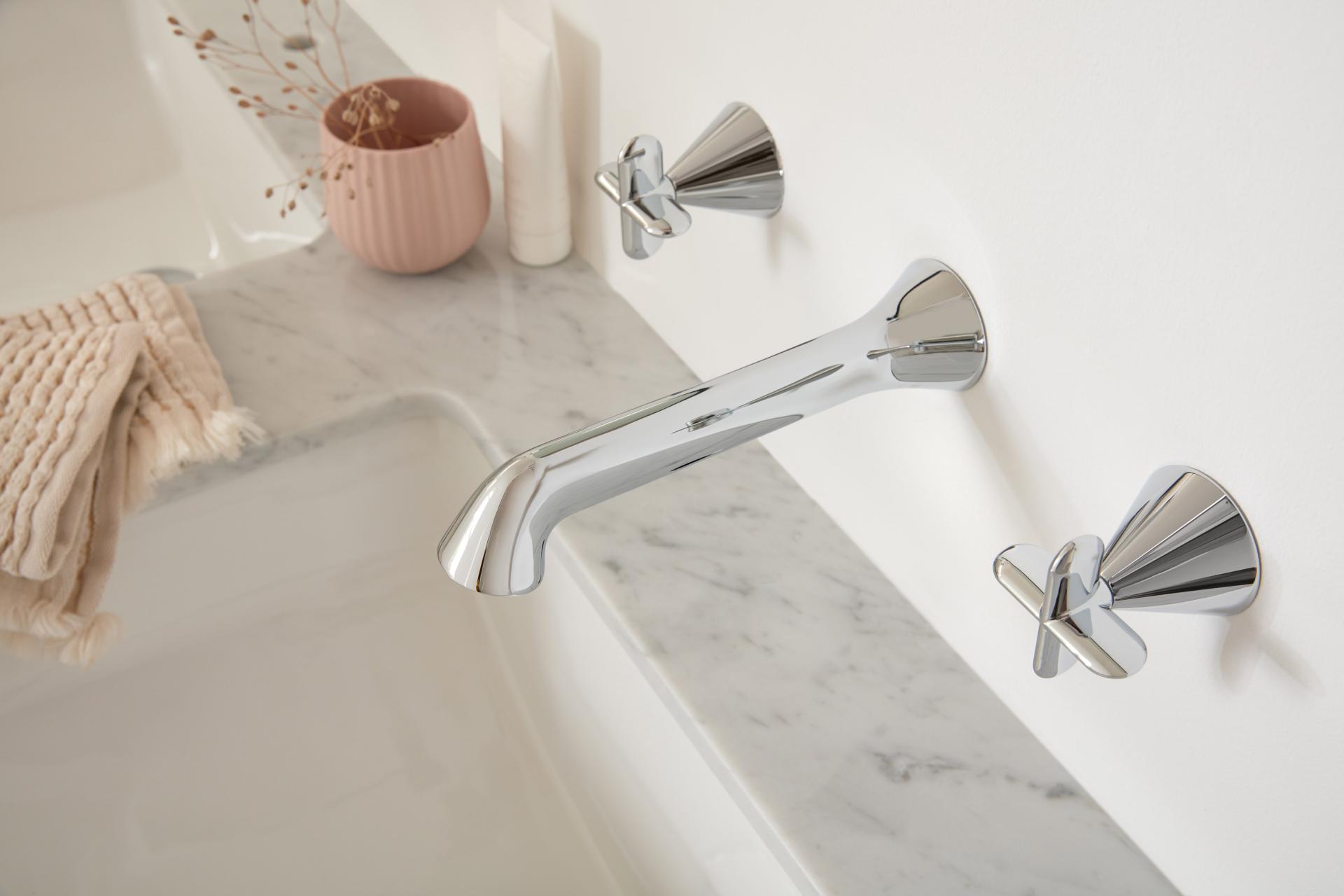 Chrome faucet fixture with stylish handles on marble countertop, showcasing VADO's collaboration with Conran and Partners.
