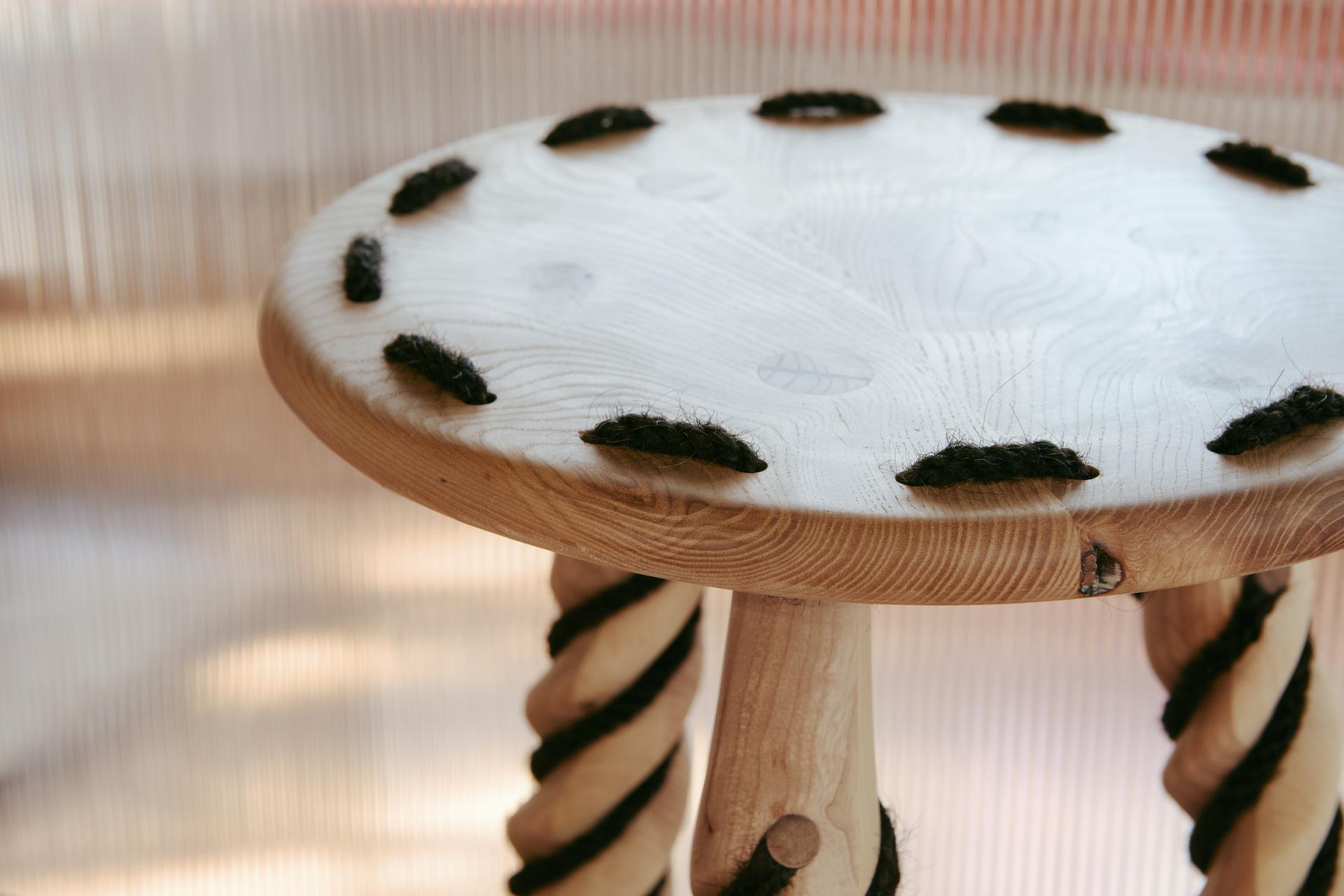 Sustainable wooden stool featuring a unique design with dark wool accents, highlighting eco-friendly craftsmanship for modern interiors.