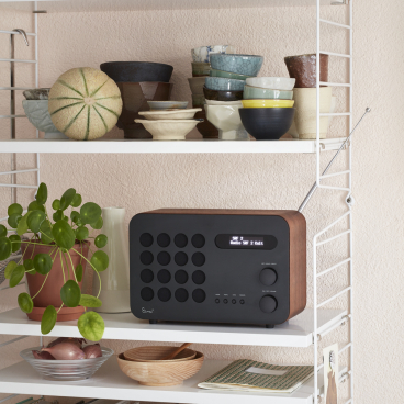 Vitra's accessories display features a radio, ceramic bowls, and a plant, showcasing contemporary design elements.