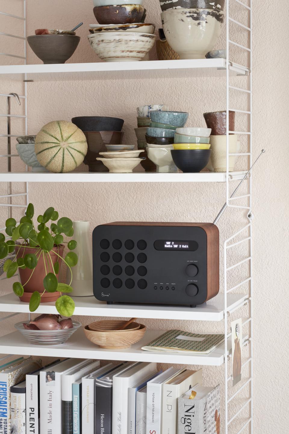 Vitra's accessories display features a radio, ceramic bowls, and a plant, showcasing contemporary design elements.