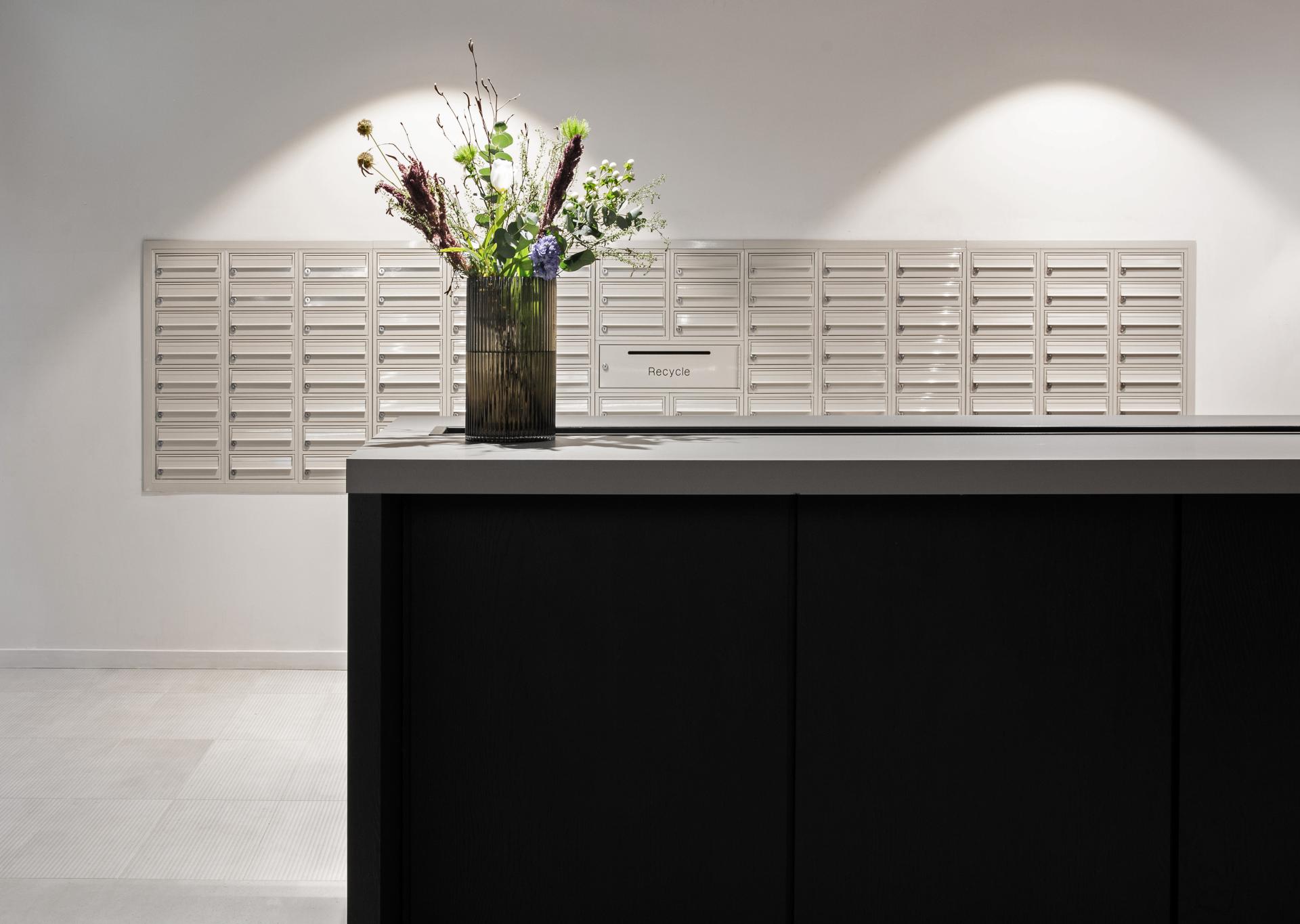 Modern reception area at Excelsior Works, featuring a striking flower arrangement and postal lockers in Manchester.
