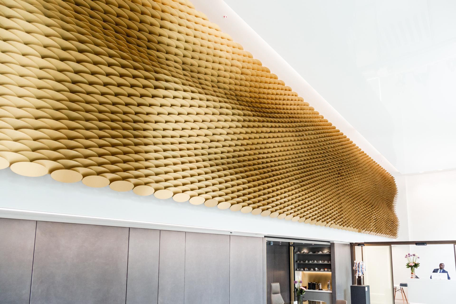 A visually striking feature wall made of layered, gold-toned circular forms, showcasing innovative material design by Giles Miller Studio.