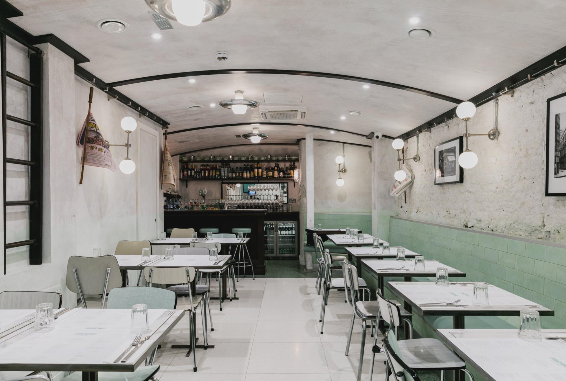 Elegant Art Deco interior featuring green and white striped decor, tables set for dining in an Italian restaurant.