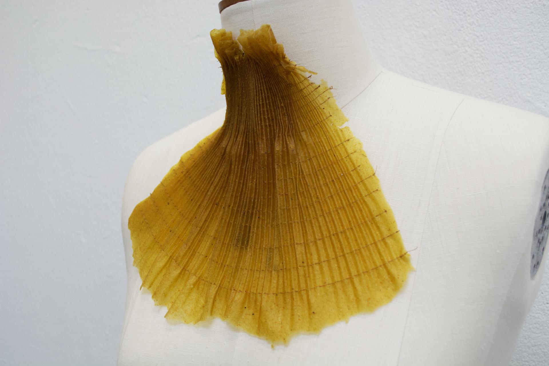 Innovative fashion design showcasing a textured yellow collar on a dress form, highlighting sustainable materials at New Designers 2024.
