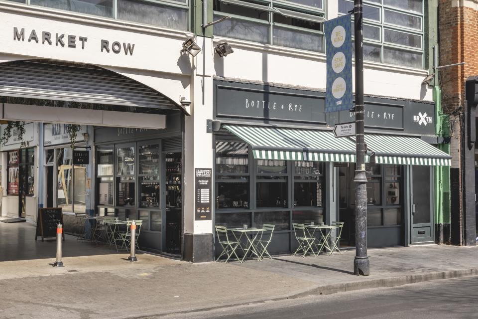 Charming Parisian-inspired wine bar and bistro, Bottle + Rye, featuring outdoor seating and vibrant storefront in Brixton.