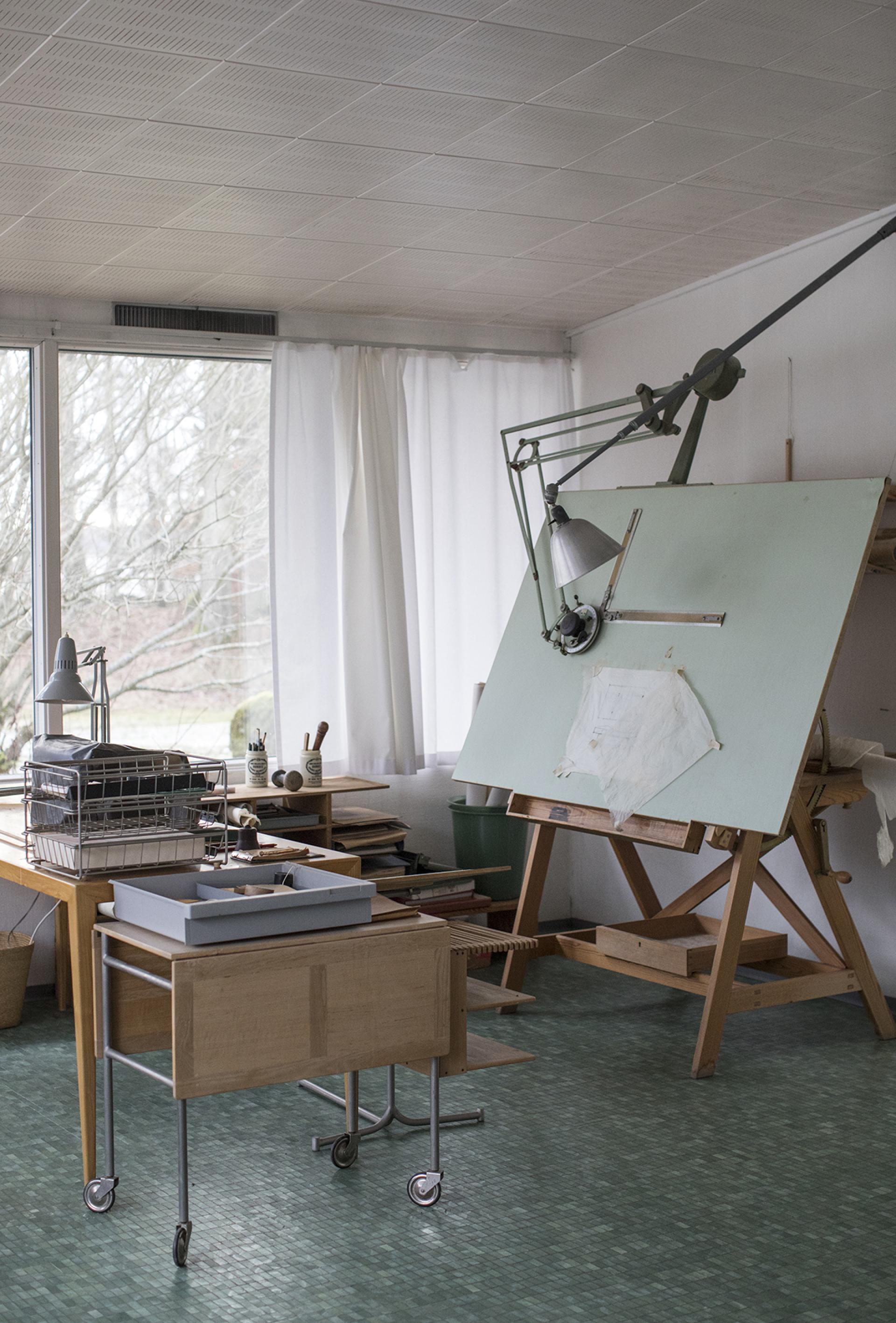 Brightly lit artist's studio in Södra Kull, featuring a drafting table, storage furniture, and natural light.