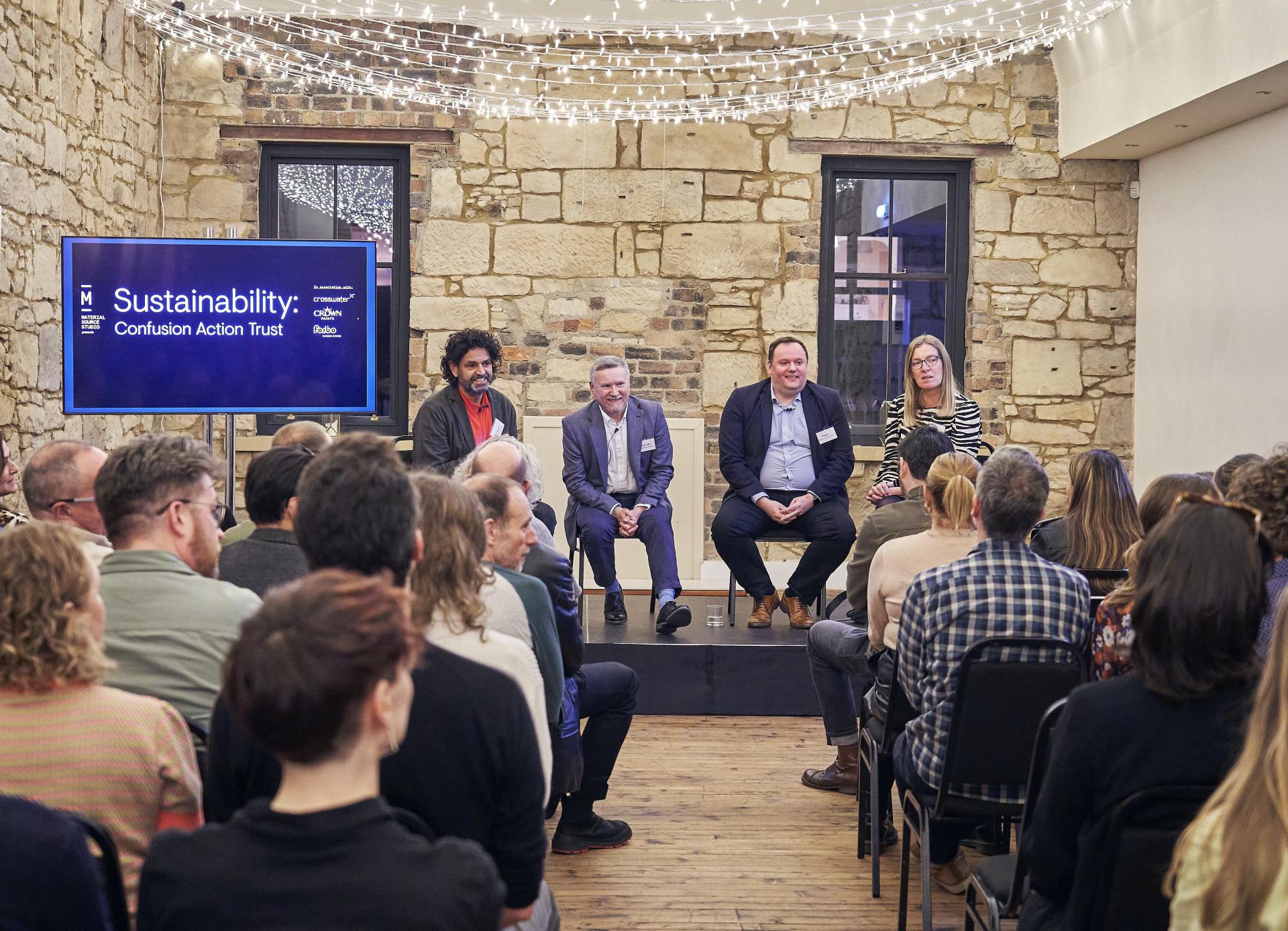 Panel discussion on sustainability featuring experts, with an audience engaged in a decorative, historic venue.