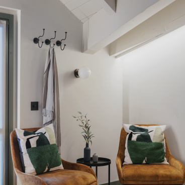 Stylish eco-friendly hotel room featuring cozy armchairs, decorative pillows, and modern design elements by Boxx Creative.