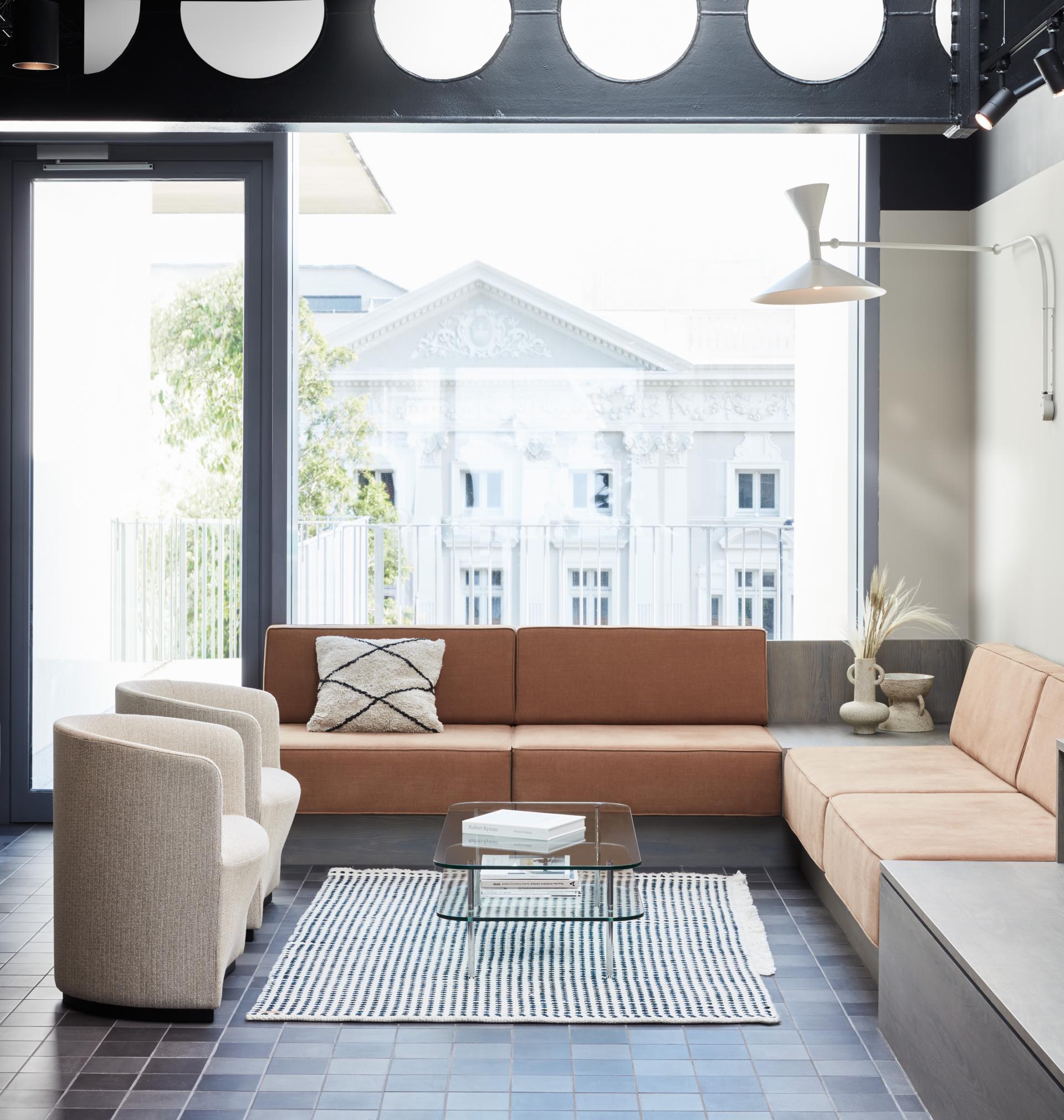 Modern flexible workspace in Notting Hill featuring stylish seating, a glass table, and large windows with urban views.