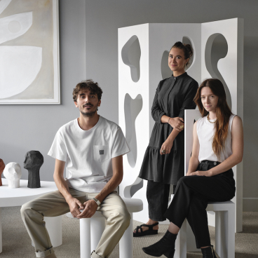 Three designers posing with unique sculptures and furniture during the London Design Festival, showcasing innovative design aesthetics.