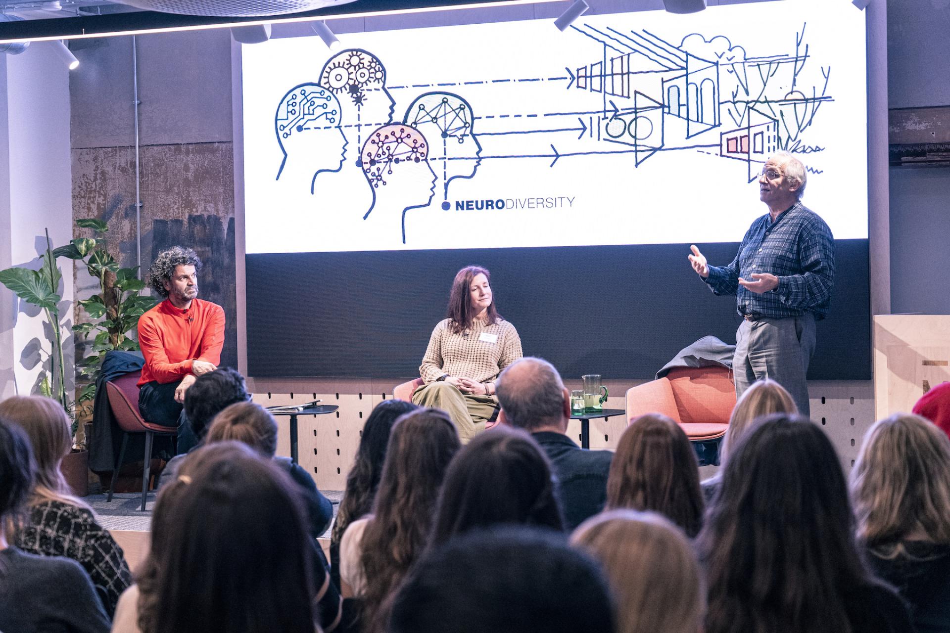 Panel discussion on neurodiversity featuring speakers, with a visual presentation highlighting diverse brain designs and architecture.
