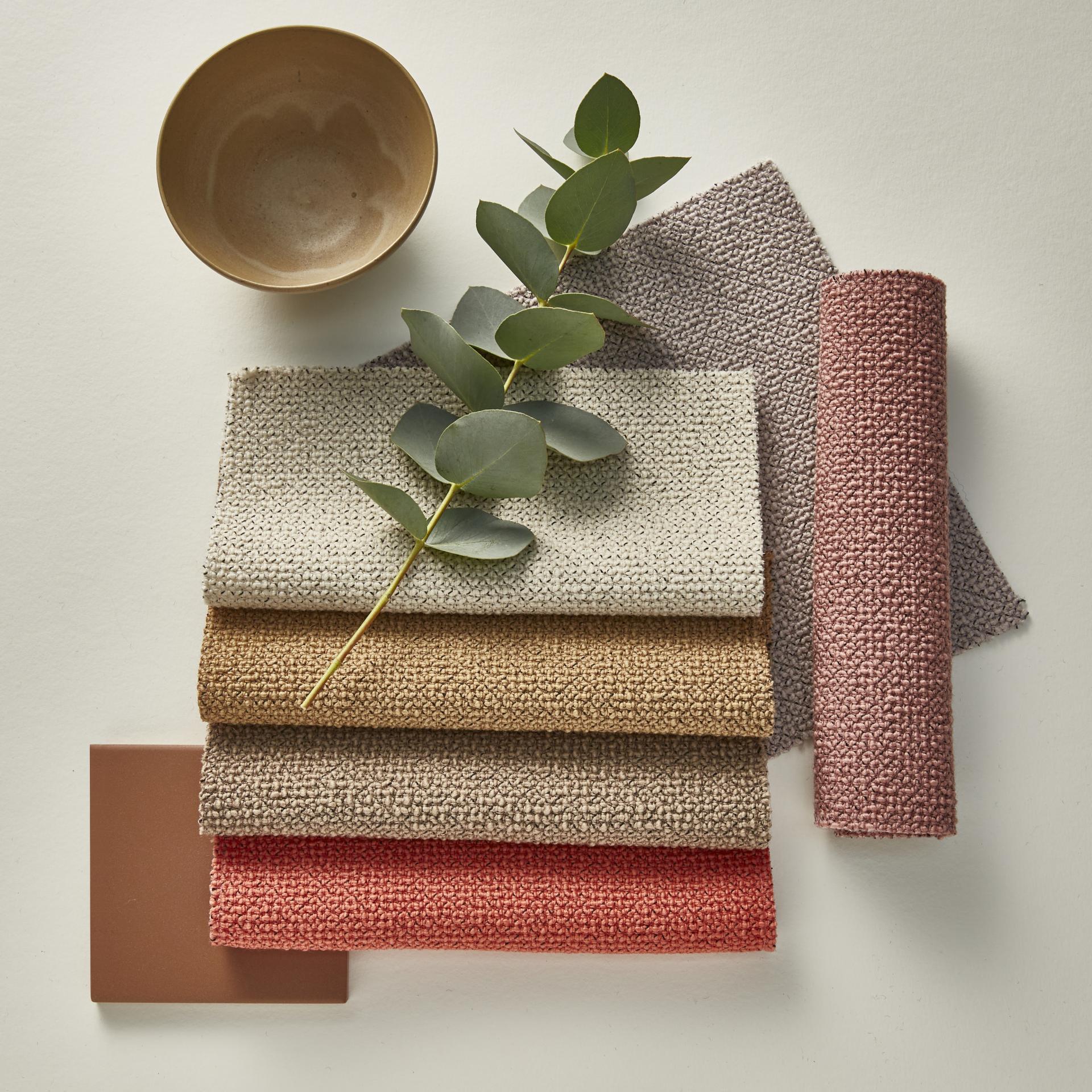 New spring shades of Camira's Yoredale bouclé fabrics displayed with a ceramic bowl and greenery.