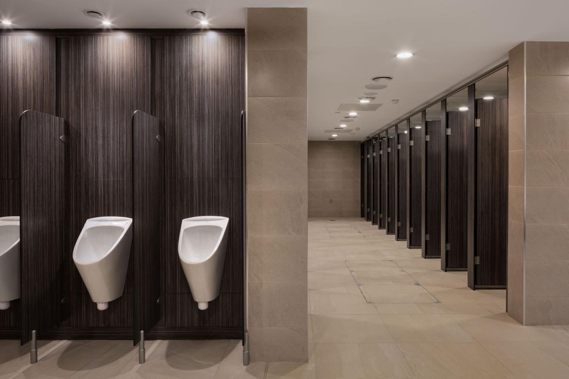 Modern washroom interior at Liverpool Street Station featuring urinals and stalls in a stylish setting.