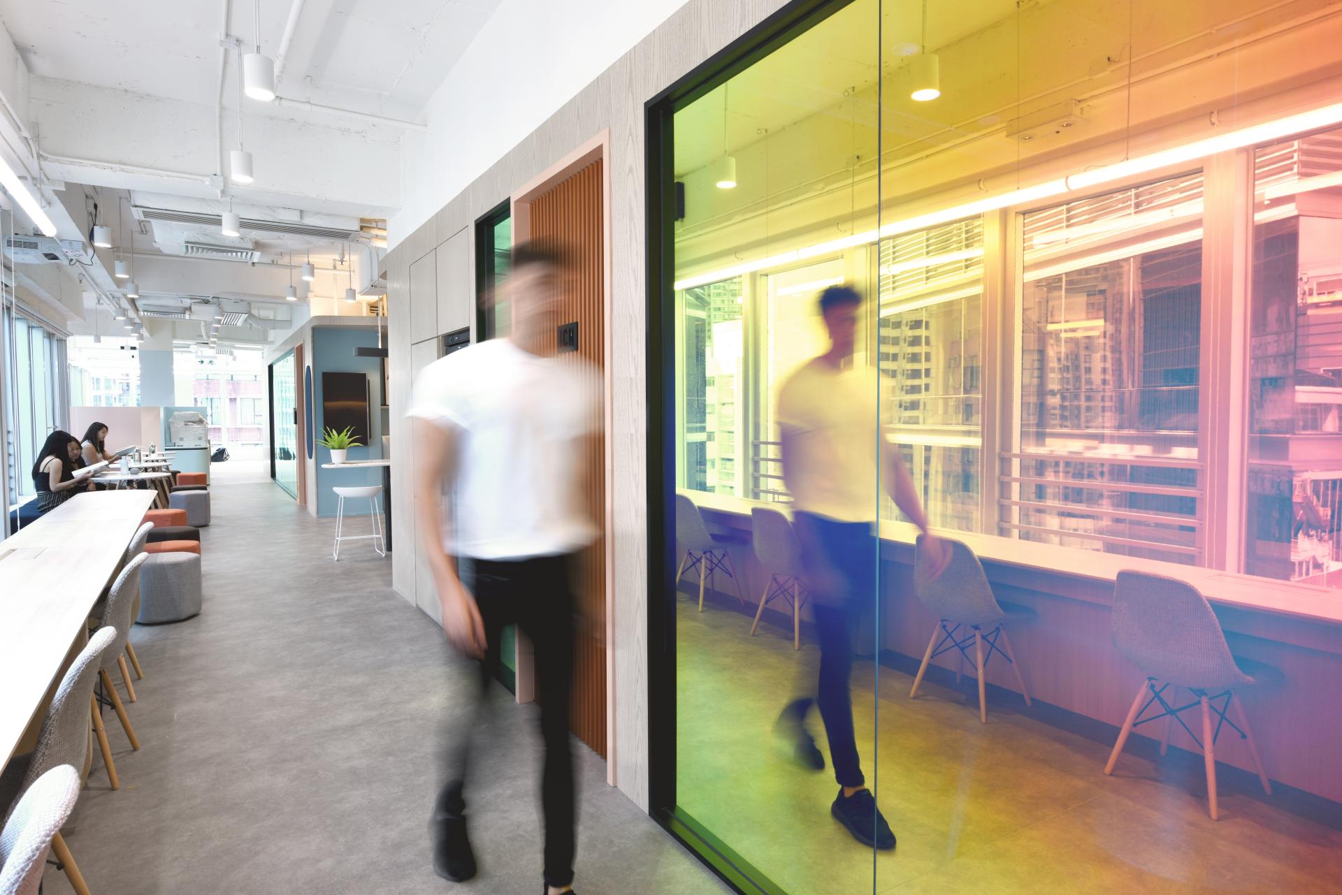 Modern office corridor with colorful glass walls, showcasing a collaborative workspace designed for travel technology professionals.
