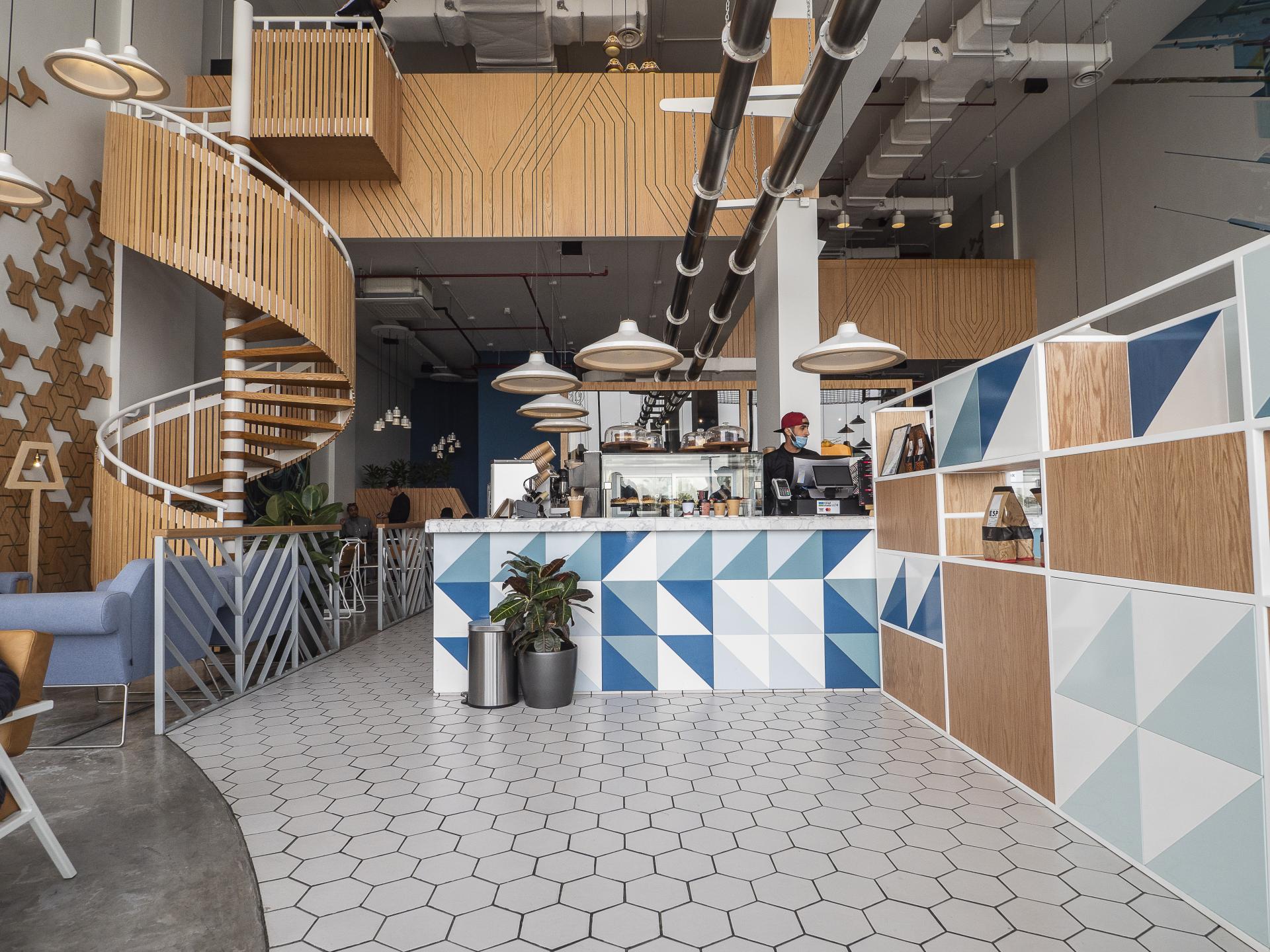 Stylish interior of Brew92 cafe featuring a geometric design, spiral staircase, and vibrant colors by Liqui Design.