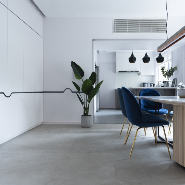 Modern dining area in Beau Cloud Mansion featuring a round table, blue chairs, and greenery, emphasizing open, airy design.
