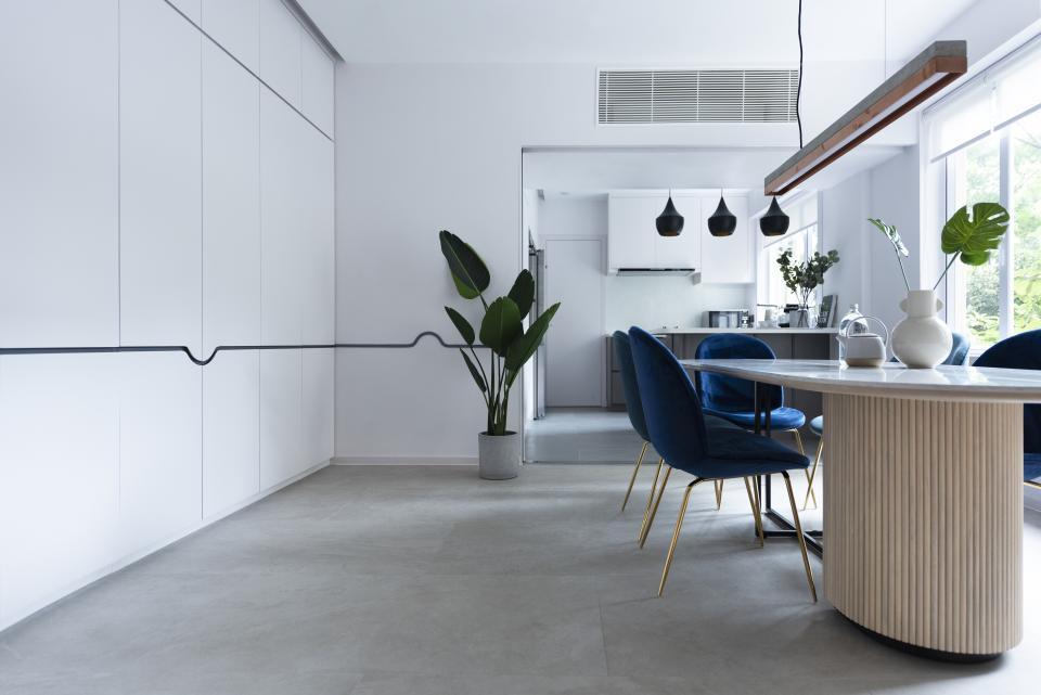 Modern dining area in Beau Cloud Mansion featuring a round table, blue chairs, and greenery, emphasizing open, airy design.
