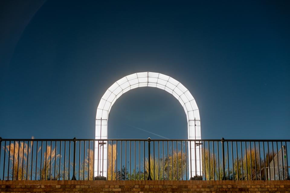 Giant sculptural light installation by Studio Mieke Meijer arching brightly against the night sky at Coal Drops Yard.