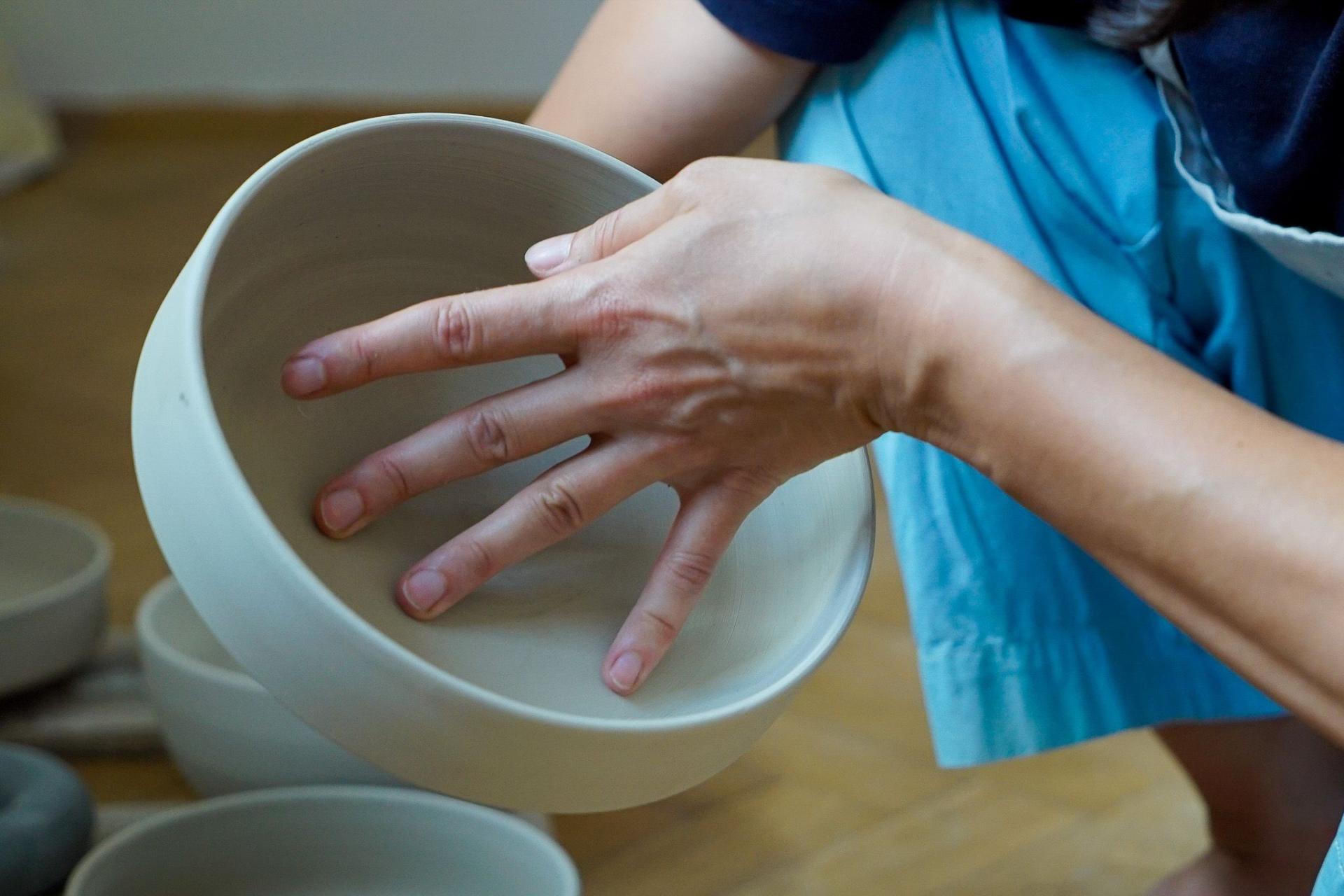 Hand of a ceramicist shaping a bowl, showcasing Sandra Berghianu's craftsmanship in functional and sculptural ceramics.